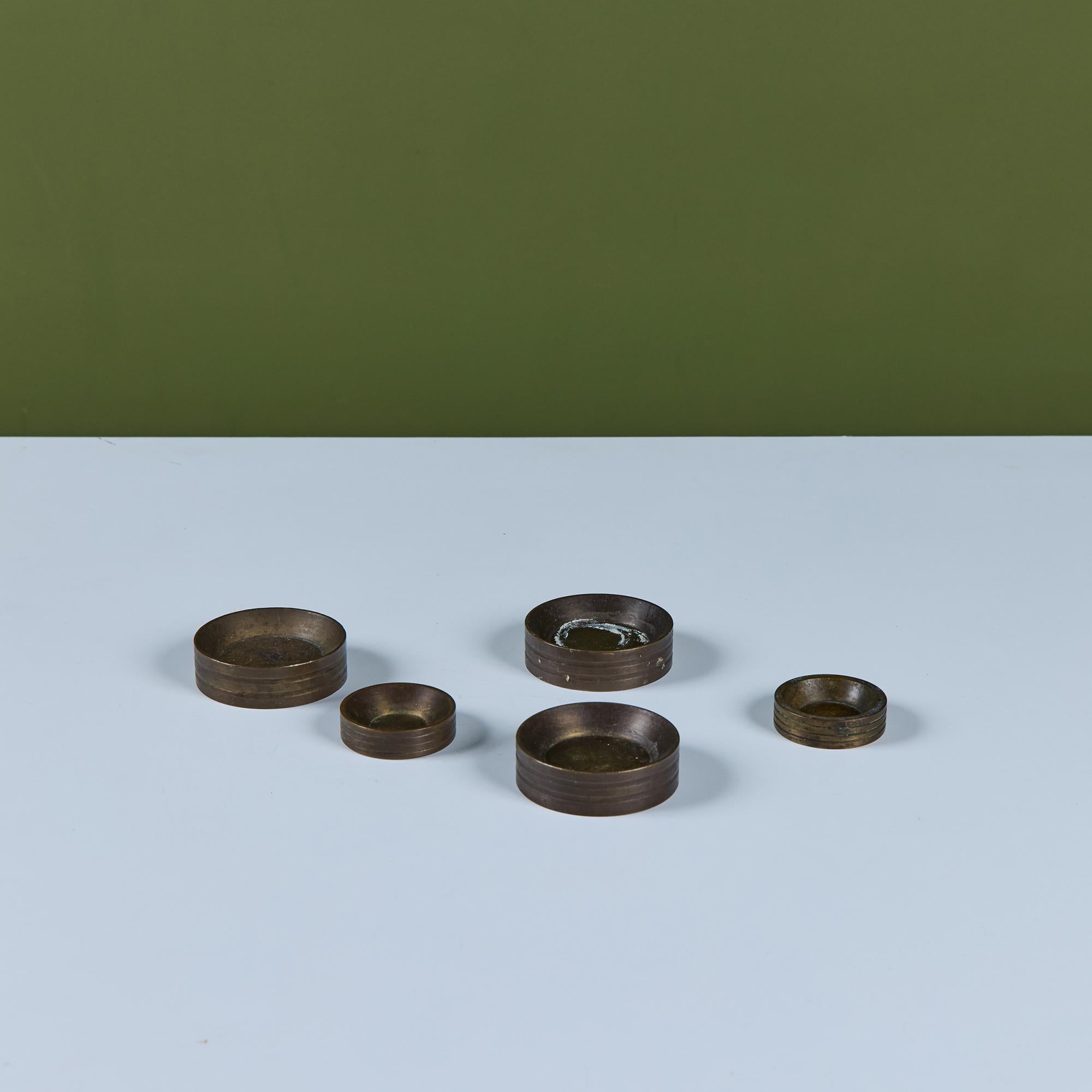 Set of five round metal weights originally used for weighing goods and things like precious materials. They would make for petite ashtrays or catchalls for rings. They can also be stacked to form a sculptural figure.

Dimensions 
3 large: 2.5
