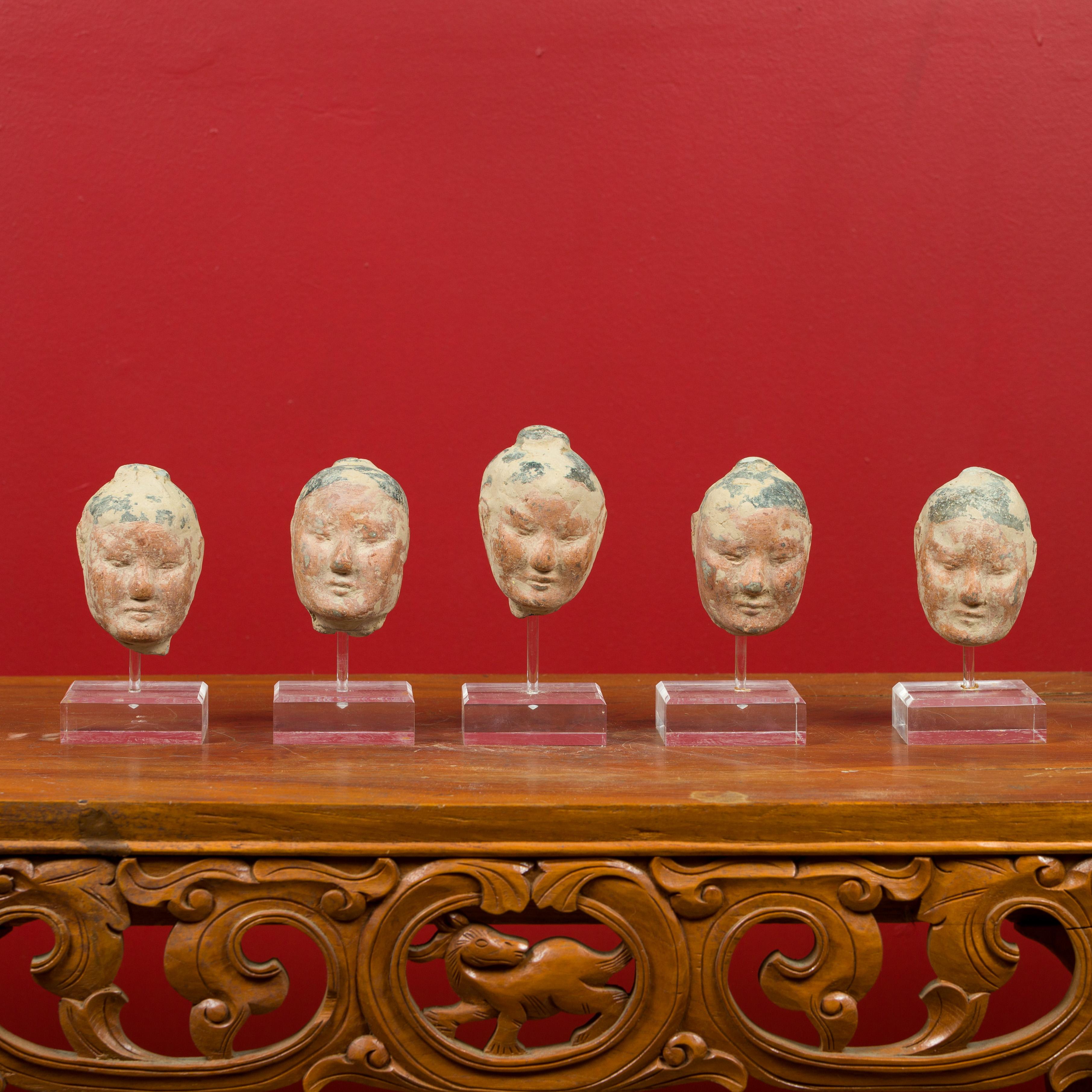 A set of five Chinese Han dynasty painted terracotta heads circa 202 BC-200 AD, all showing slight variations and mounted on custom made Lucite stands. The set is priced at $2,950, but we are also willing to sell them individually for $590 each.