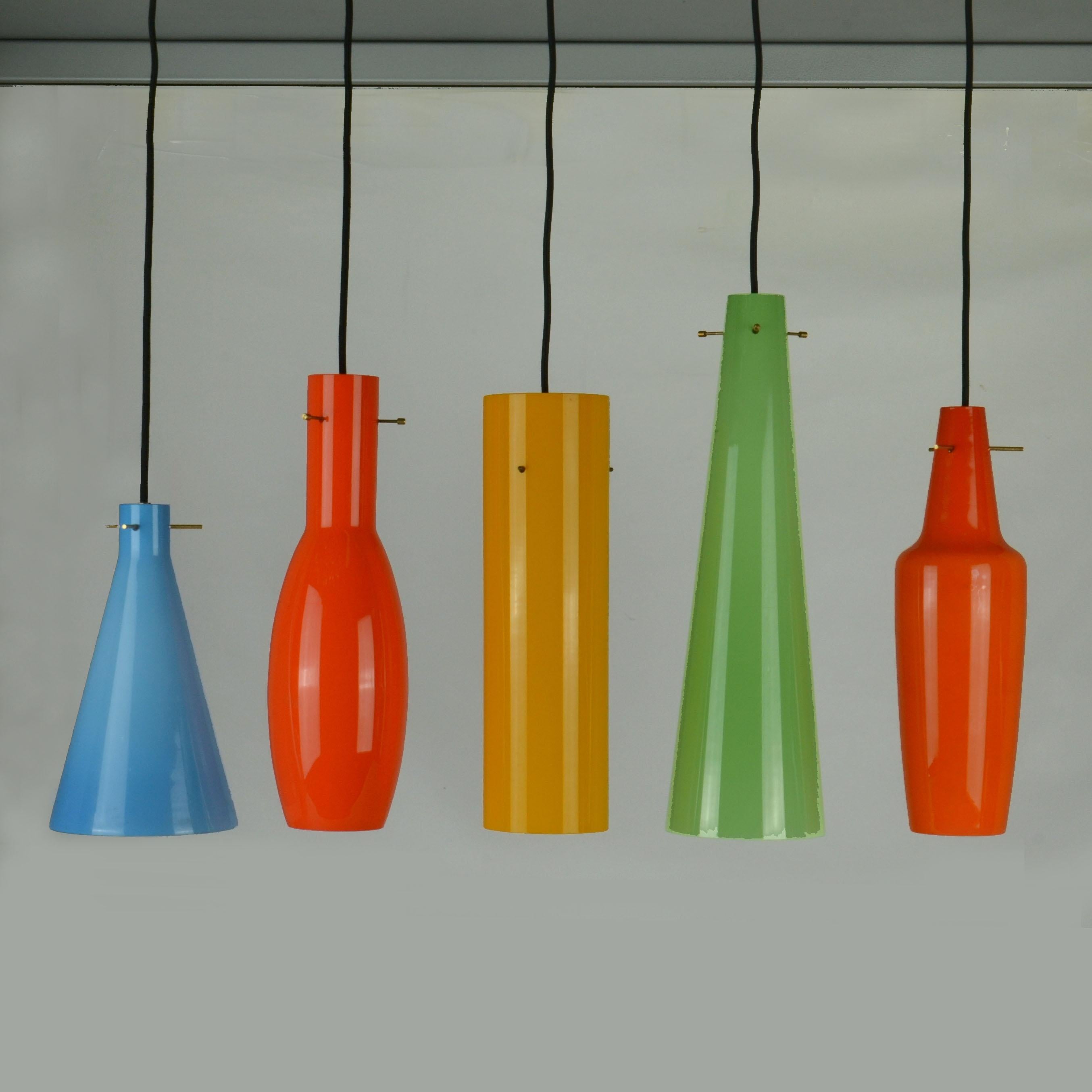 Cinq pendentifs en verre Vistosi de différentes formes et tailles en orange foncé, bleu, jaune, orange clair et vert, années 1950, Italie.
Les abat-jours en verre sont suspendus à une structure centrale de trois broches, un système à trois tiges en