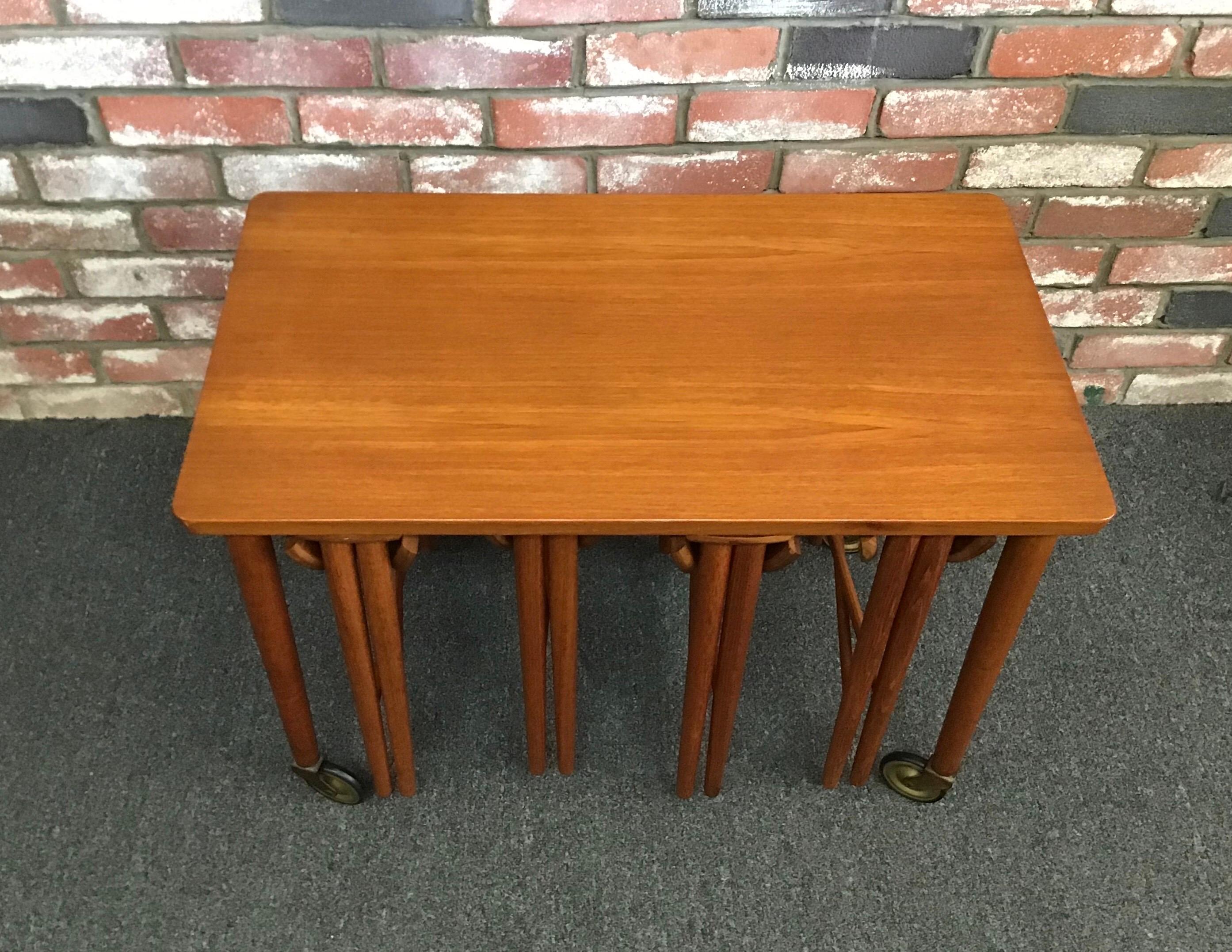 Ingenious set of five Danish modern nesting tables by Carlo Jensen for Hundevad, circa 1950s. A very nice rectangle side teak side table (on removable wheels) stores four individual small round folding tables. This super rare piece is a great