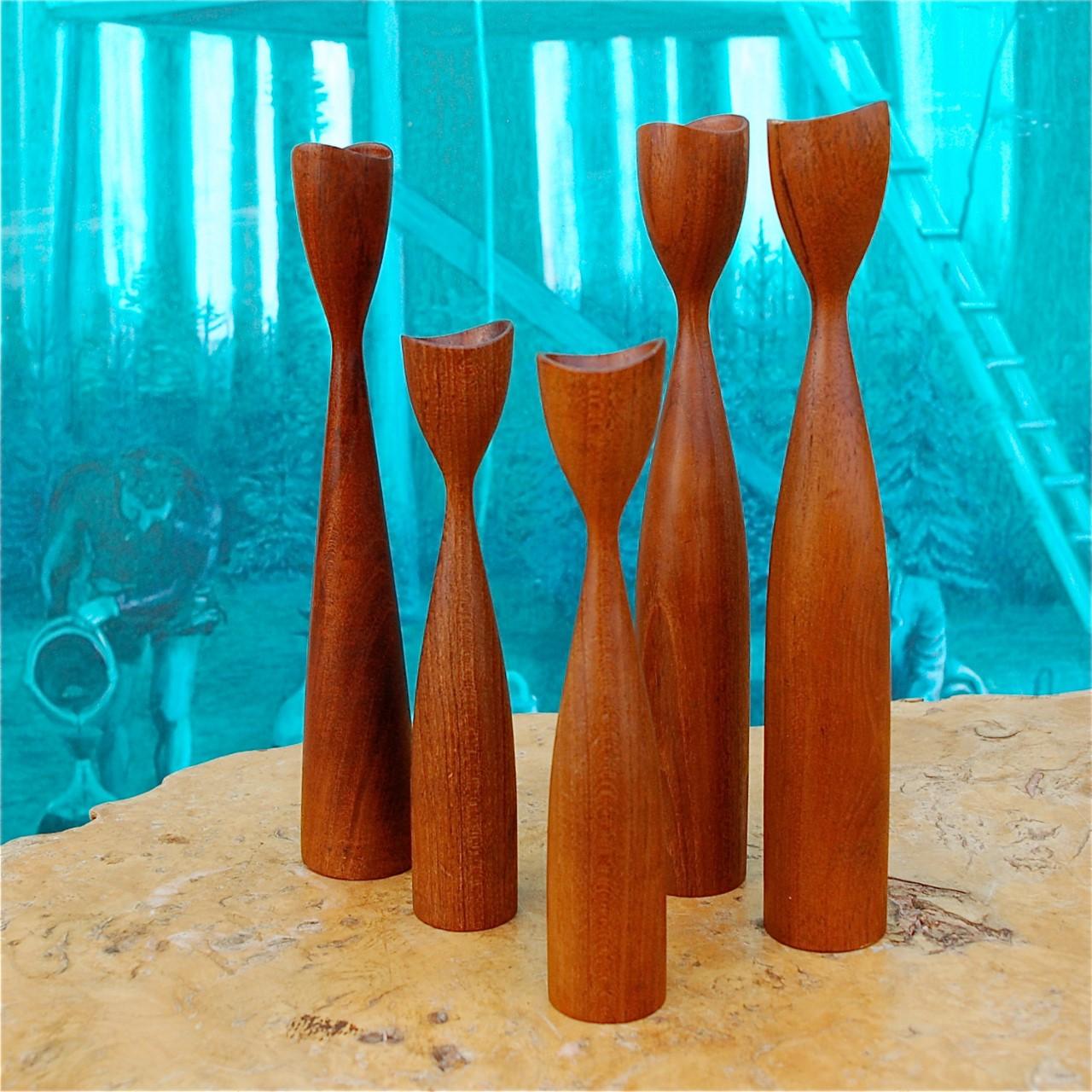 Set of 5 solid turned teak, wooden Danish candleholders. The pieces are different in size and we have put them together as a set. The teak has a lovely depth of color and grain. Their tapered, elongated, elegant shape makes them very tactile pieces.