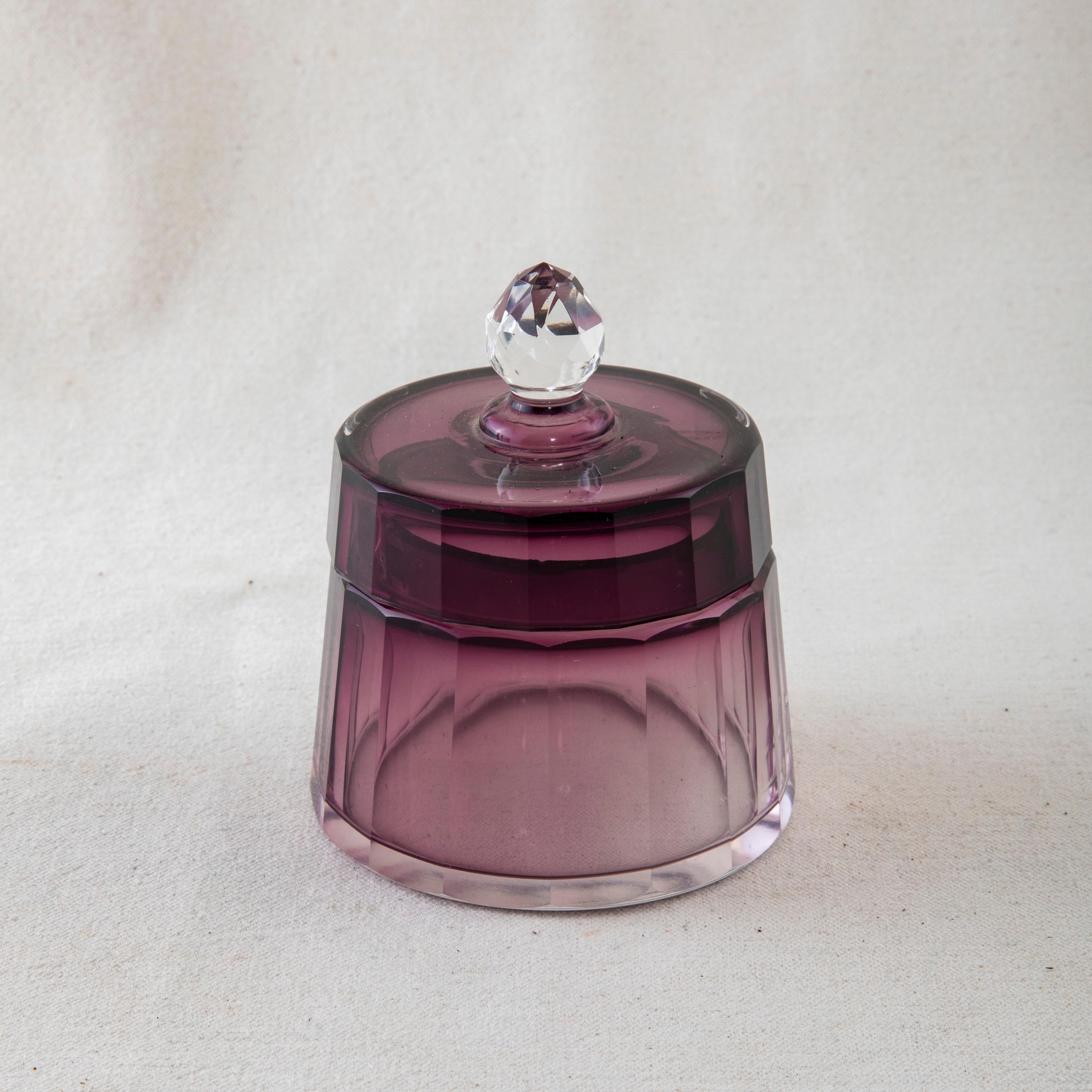 This set of five early twentieth century crystal vanity bottles features an amethyst gradient on the faceted facades. This set includes a perfume atomizer, three bottles with faceted stoppers, and one jar with lid. The bottles range in heights from