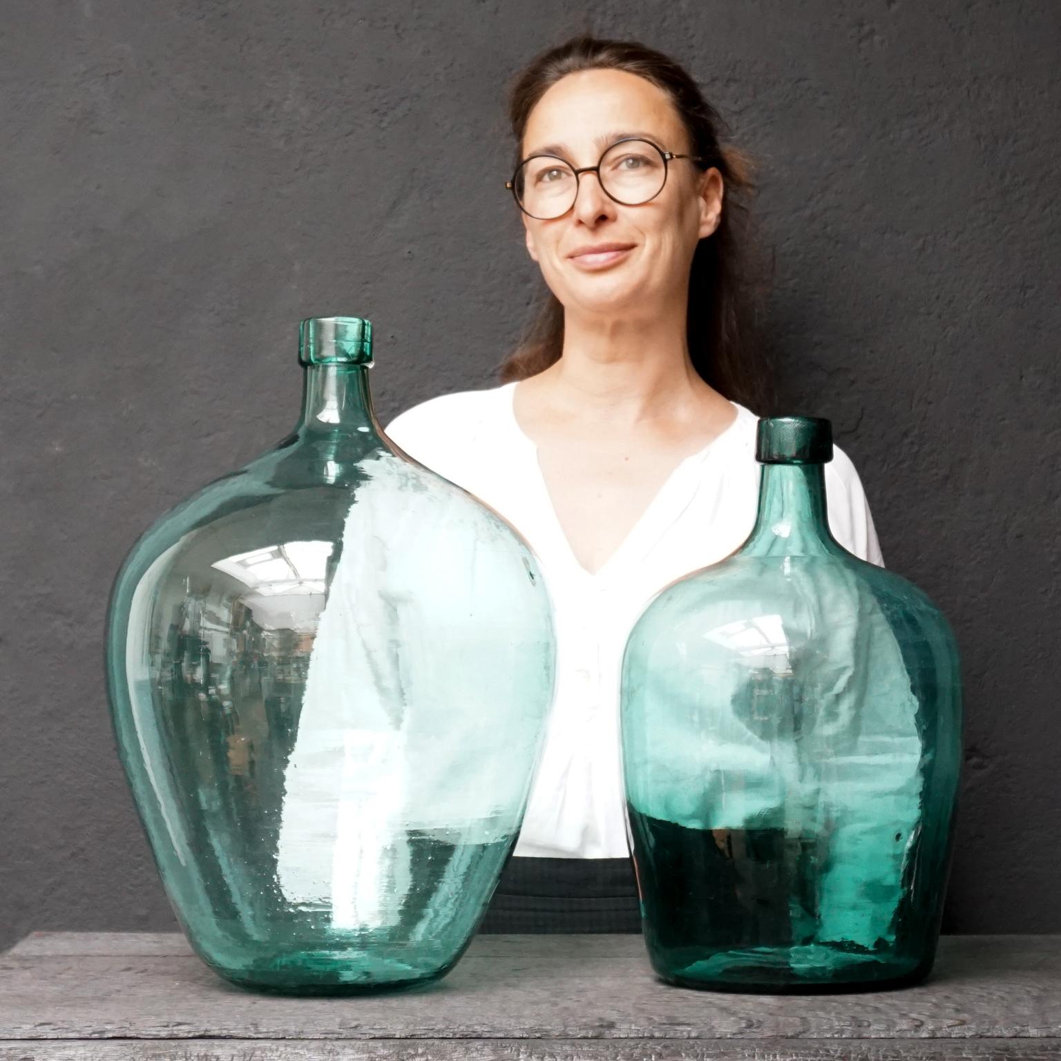 Very decorative set of 5 old blue-ish green blown glass bottles know as Demijohn, Lady Jeanne or Carboy. 
Made and used somewhere between 1900 and 1950. 

Three of them have a capacity of 20 Liters or approximately 5.3 US Gallons or 4.4 UK