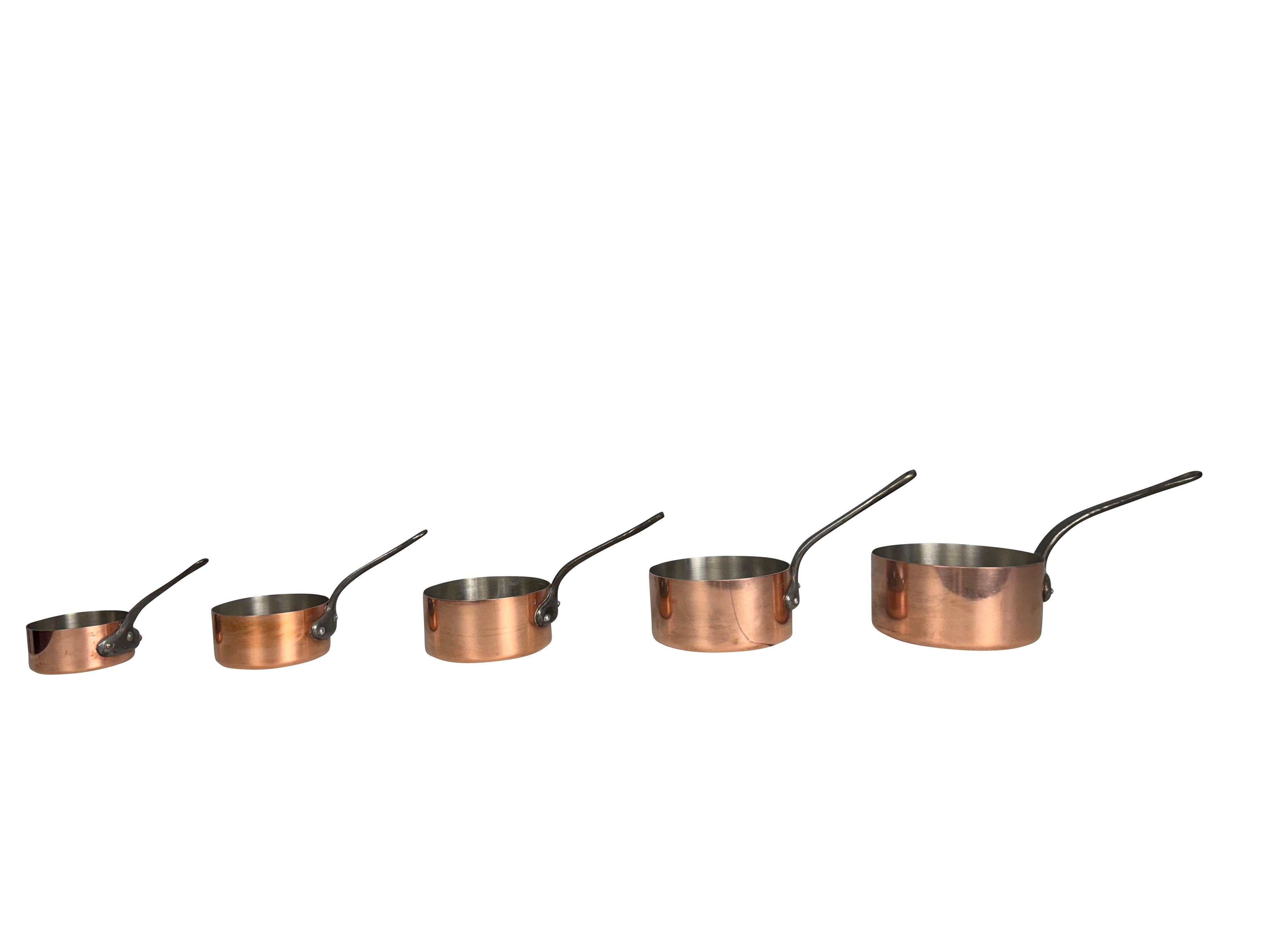 Un ensemble de 5 casseroles graduées en cuivre avec des poignées en fer. Un magnifique ensemble de 5 casseroles en cuivre vintage, un must pour votre cuisine d'inspiration française. Fabriqué dans la première moitié du 20e siècle, cet ensemble de 5