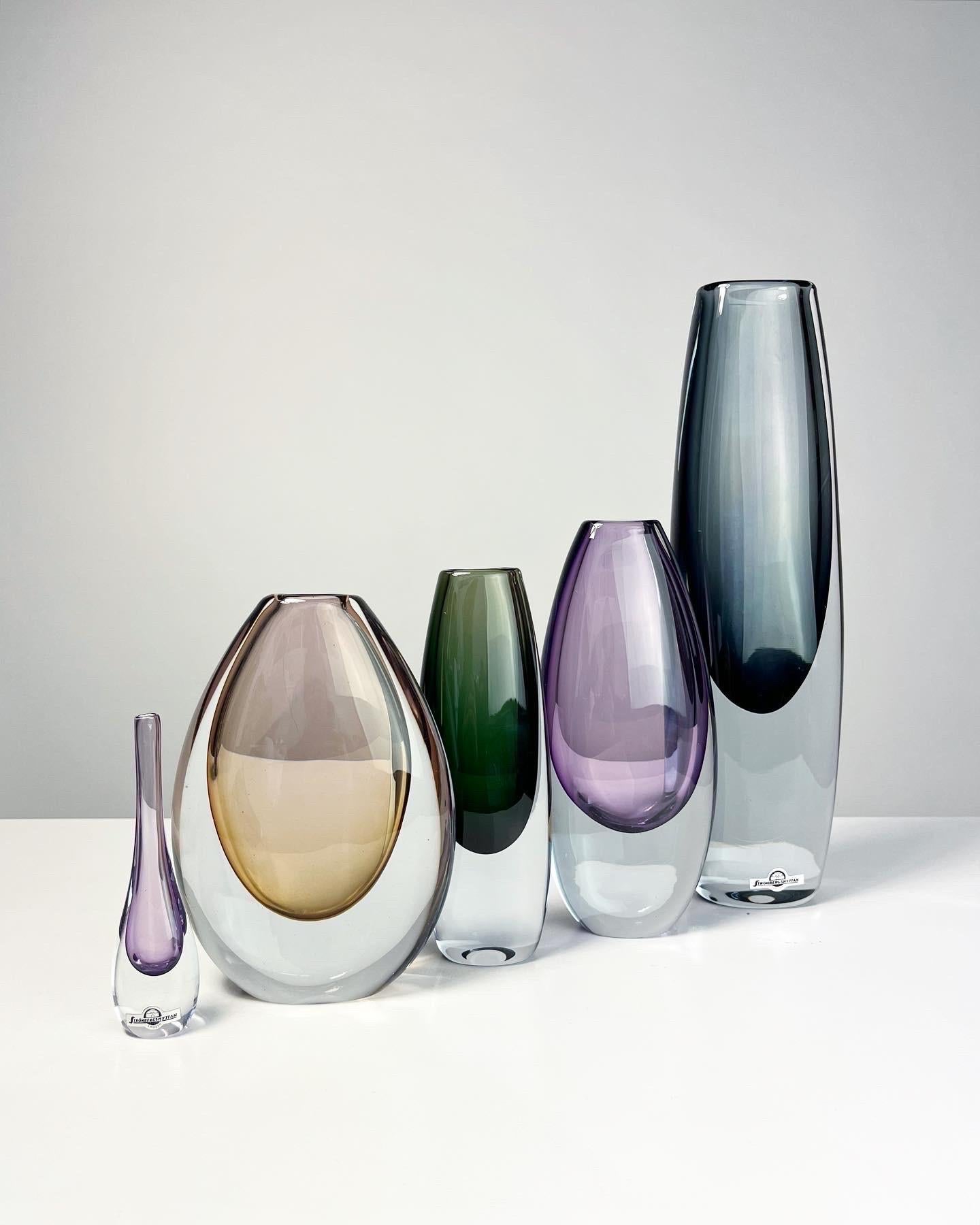 Gunnar Nylund vases in colored and clear crystal for Strömbergshyttan, Sweden 1960s.

Left to right for individual details:

• Amethyst, signed, h: 22 cm, small chip

• Dark green, model B936, signed, very good condition, h: 19 cm

• Large