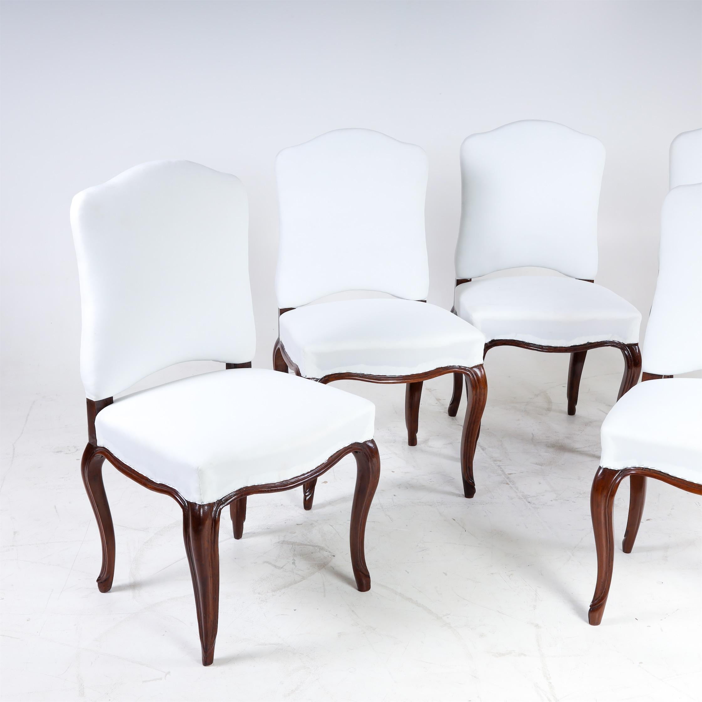 Ensemble de cinq chaises baroques sur pieds en S incurvés avec assise et dossier tapissés. Les chaises ont fait l'objet d'une finition experte et ont été recouvertes d'un tissu de base blanc.
