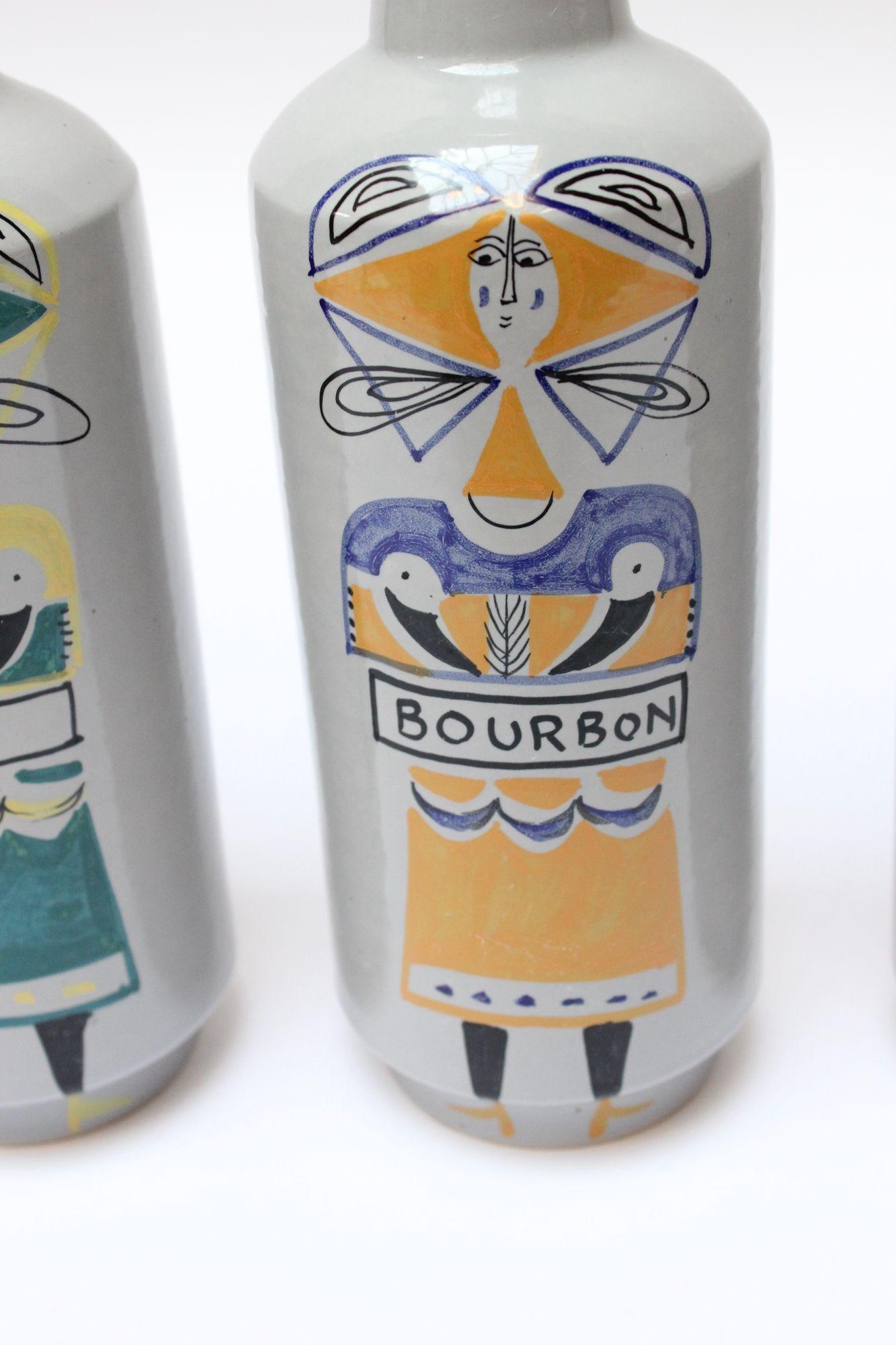 Scarcely seen set of five ceramic spirits bottles with original stoppers by Raymor (ca. 1950s, Italy). Each has a hand-painted figure in an individualized color indicating a specific spirit (Bourbon, Scotch, Gin, Vodka, and Rye). Charming grouping