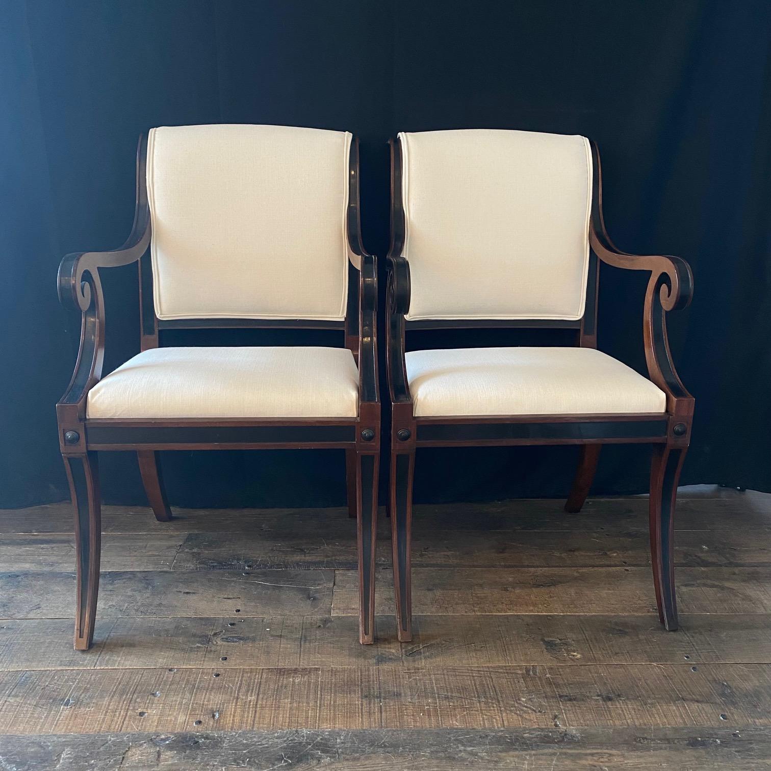 A spectacular set of klismos dining chairs: ebony and mahogany Neoclassical style with new neutral high end upholstery designed to showcase the classic design of each chair. Two armchairs and three side chairs. Decorative wood frame rising on four