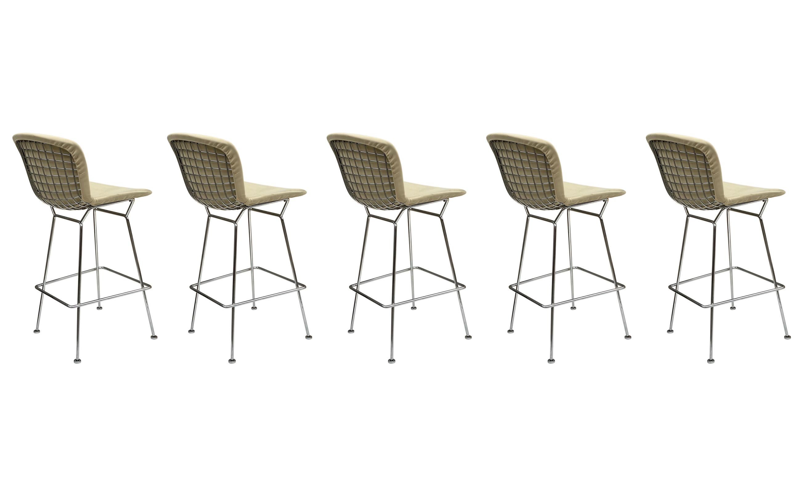 An iconic and authentic set of five barstools designed by Harry Bertoia and produced by Knoll. These consist of heavy heavy chrome plated frames with tan covers. Signed twice with paper label and stamped frames.