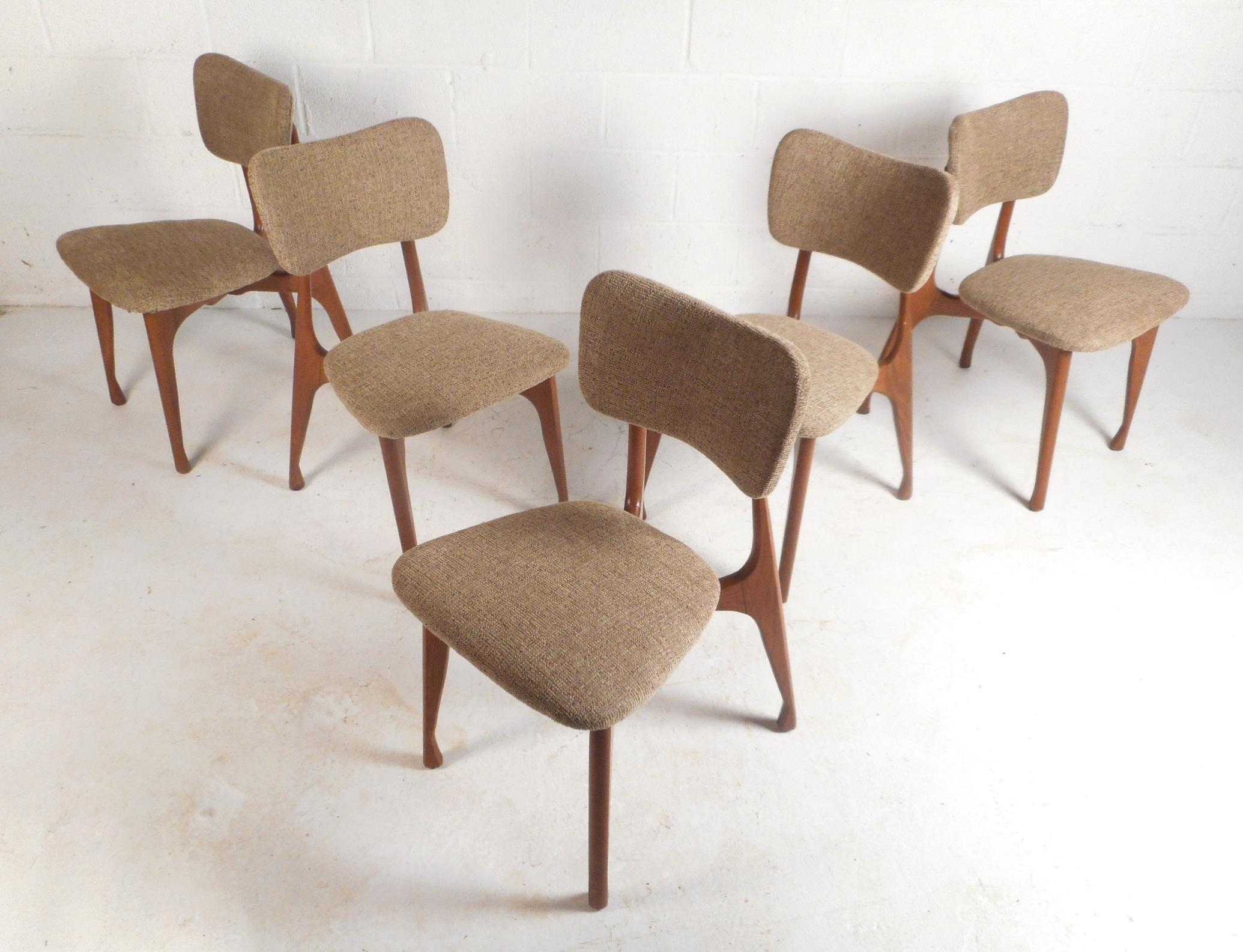 These Mid-Century Modern dining chairs feature tapered legs with sculpted feet and a vintage walnut finish. An extremely stylish and comfortable set with curved back rests and thick padded seats. The elegant beige colored upholstery and sculpted