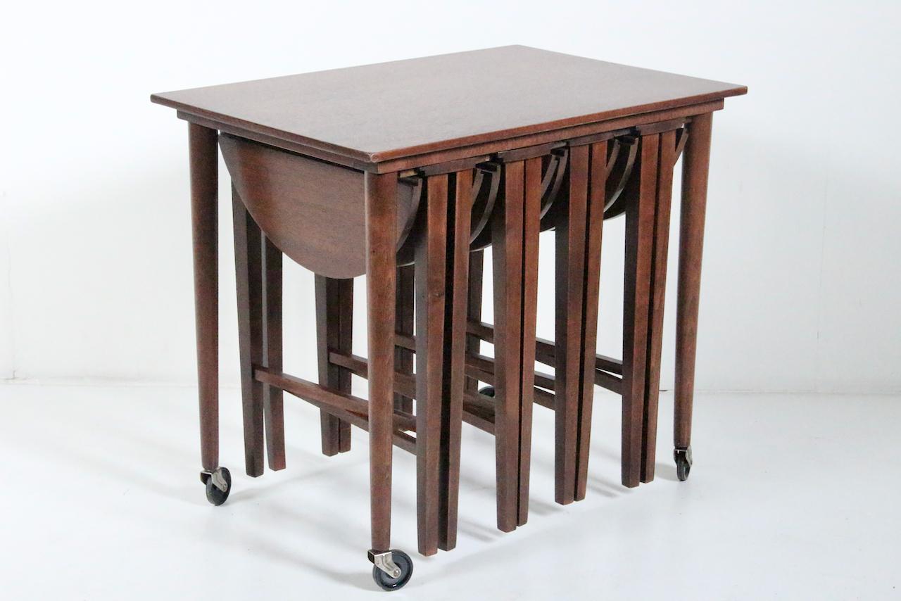 Set of 5 Danish Modern Poul Hundevad Denmark for Novy Domov Walnut finish Nesting Tables. Featuring a rectangular trolley on four casters, 4 individual, (1/2H) round, drop leaf folding occasional tables. Tables hang underneath the rectangular