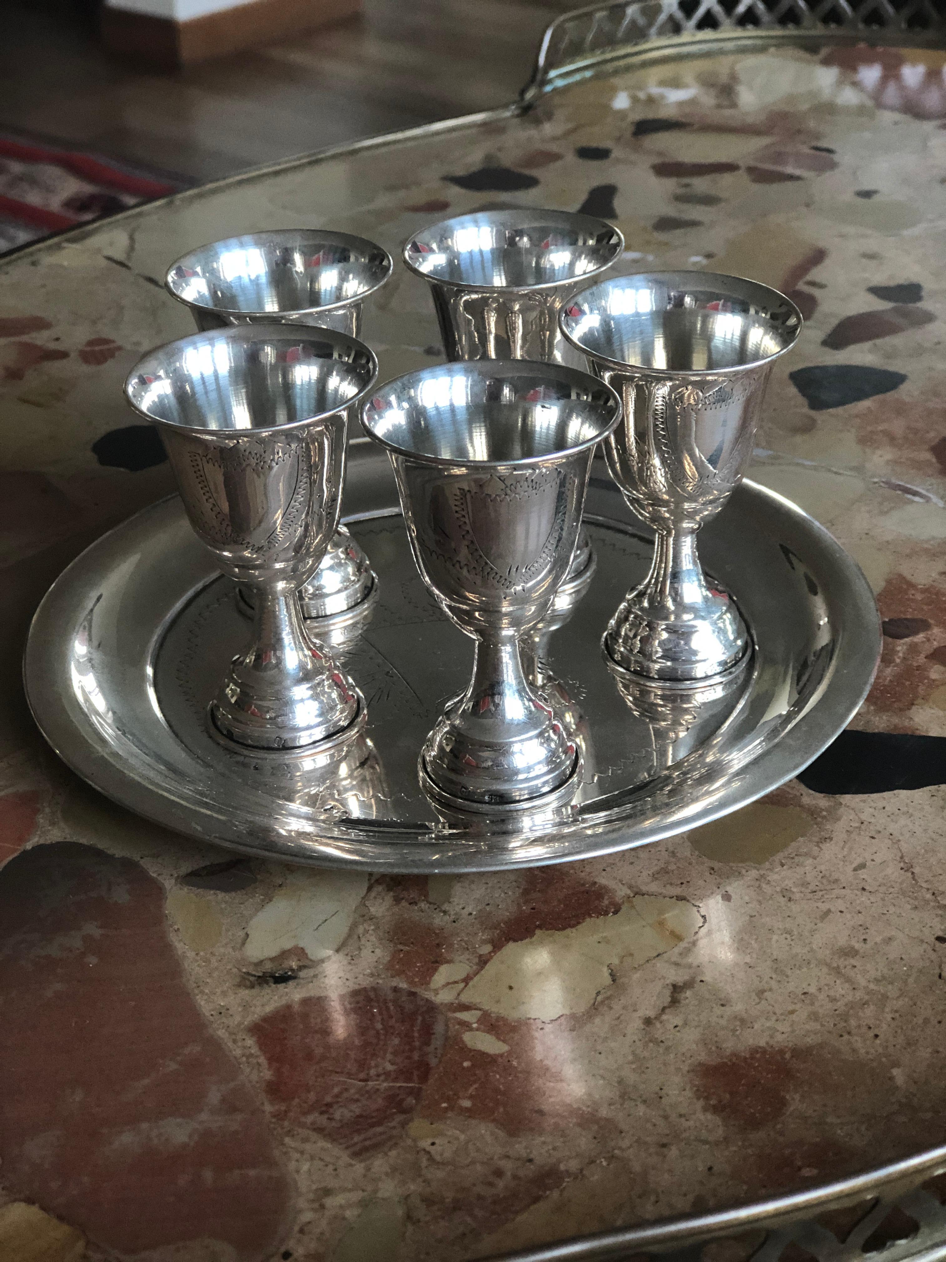 Elegant set of five cups and a small serving tray in sterling silver. All of them have a decoration as a frame where could be made an engraving.
France, circa 1900.