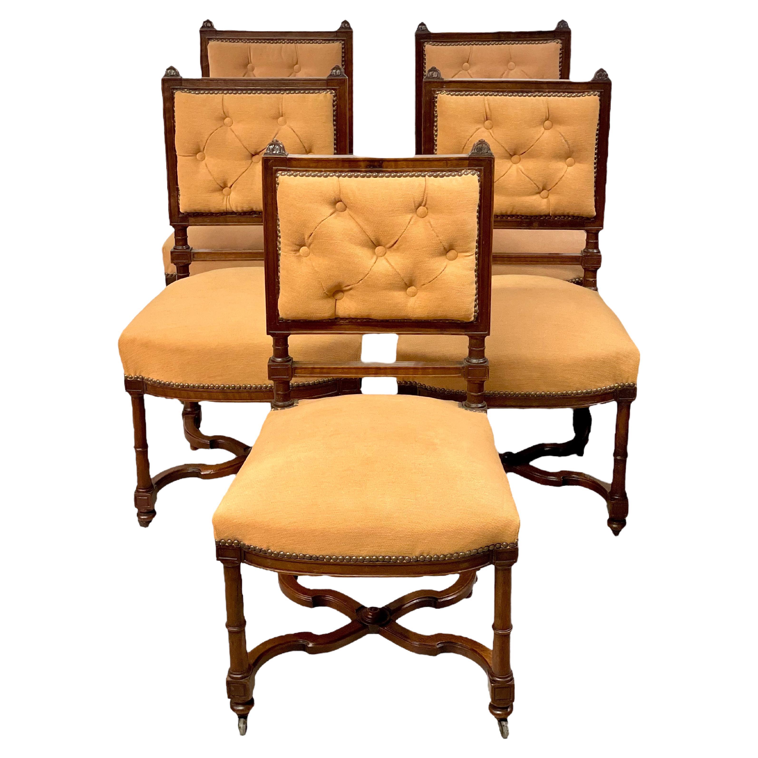 A very stylish set of five Louis XIII-style dining chairs, each one featuring a padded scrolled button back and over-stuffed seat, upholstered in a pale gold fabric and secured all round with nailhead trim. The chair legs are slim and beautifully