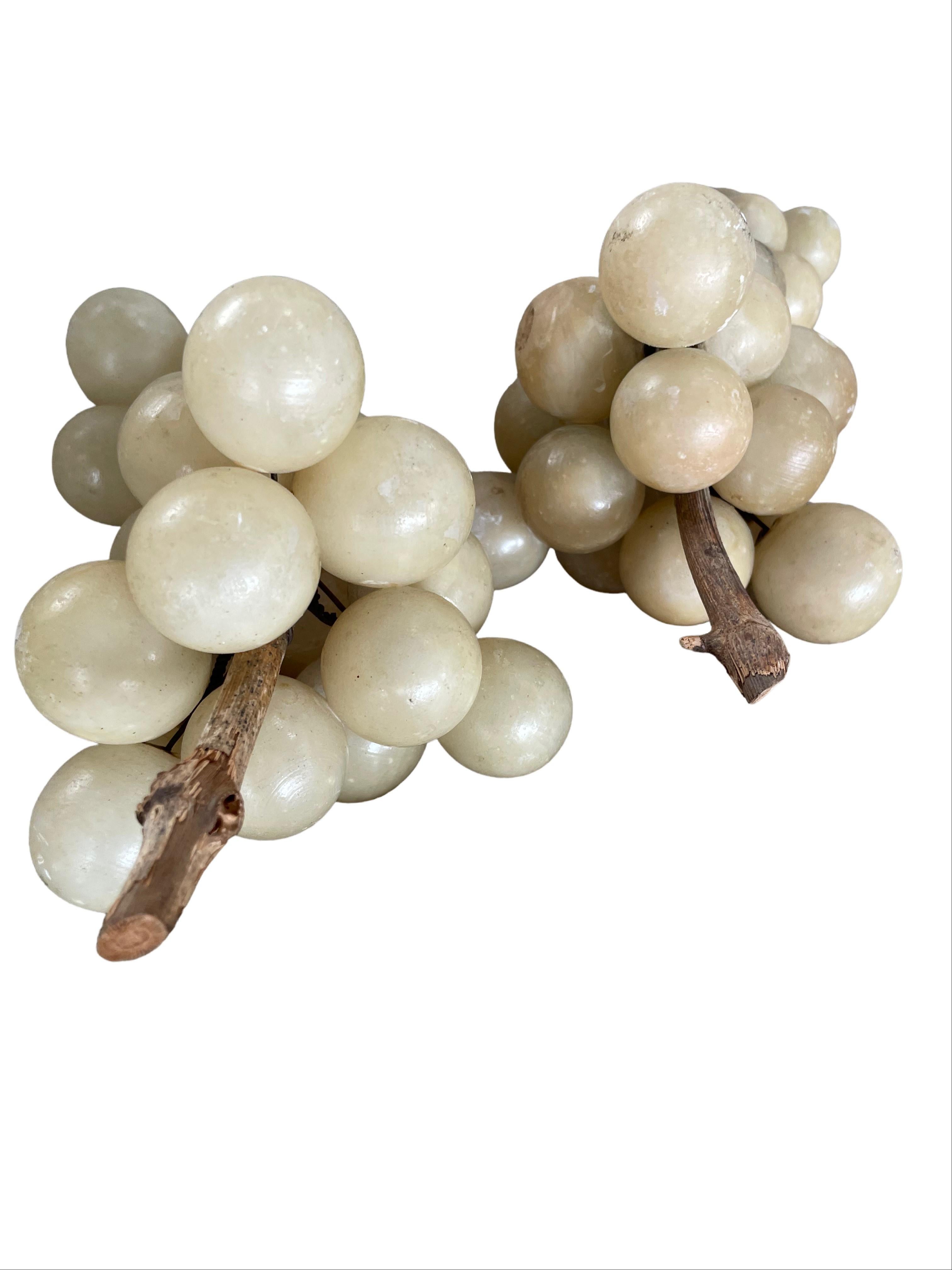 This set of Mid-century handcrafted alabaster grape clusters with wood stems transports one to the vineyards of Italy. Consisting of two large and three small clusters, the rich warm hues of alabaster stone paired with the authentic wooden stems,