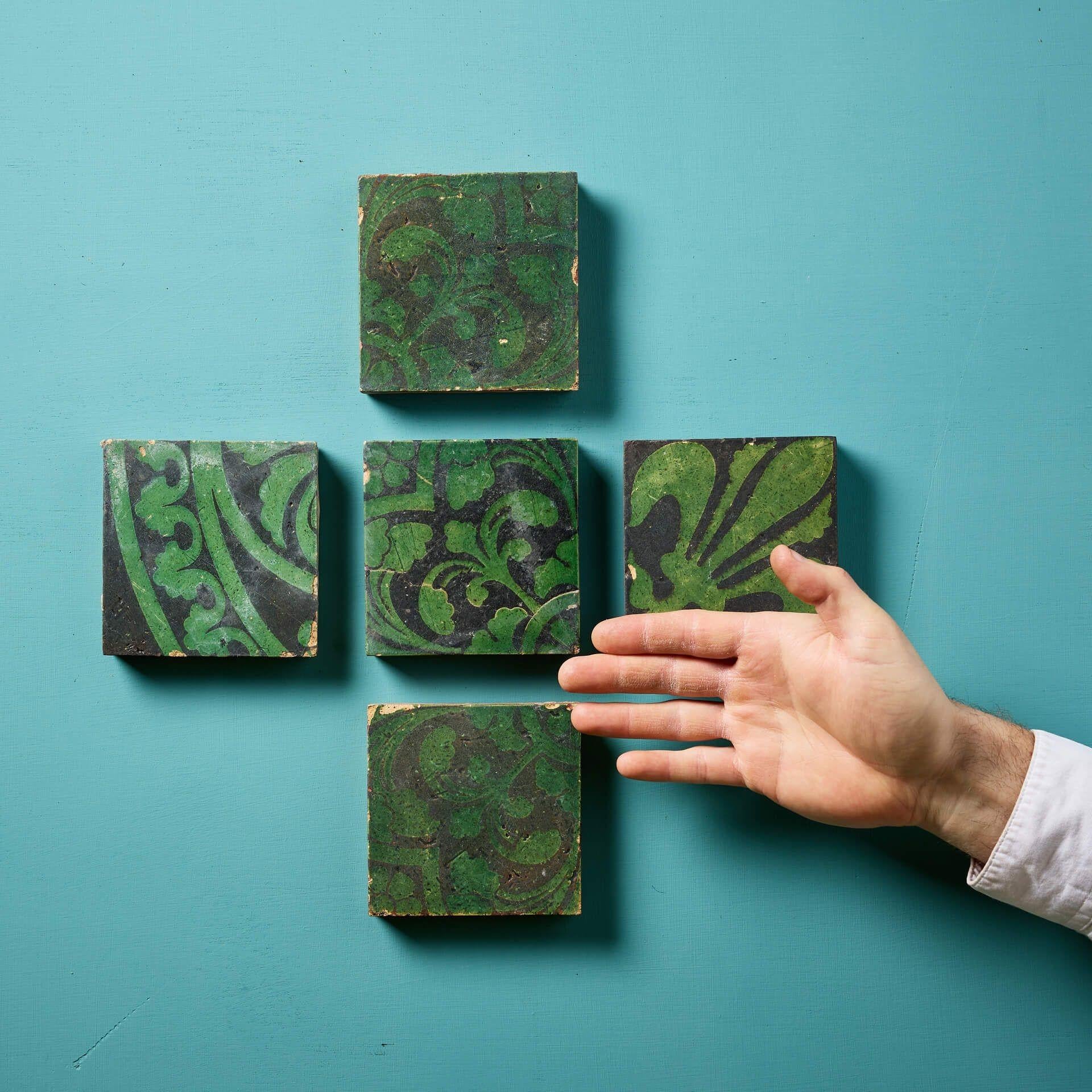 A set of five terracotta encaustic tiles by W Godwin, Lugwardine. 

These 4 inch tiles depict unglazed fleur de lys floral green patterns with a black background.

These reclaimed tiles have been in use for over 160  years and as such have a