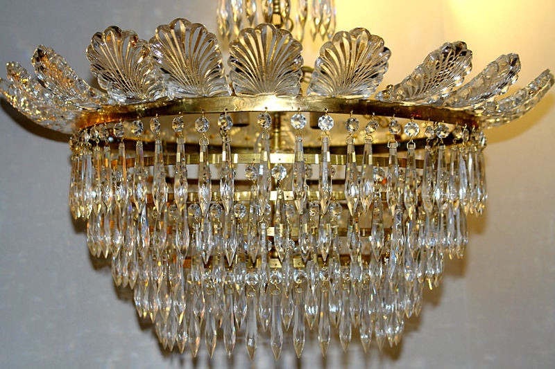 A set of fourteen French circa 1930s six-light gilt bronze flushmounted chandeliers with crystal drops on a tiered body crowned with crystal acanthus leaves. Sold individually.

Measurements:
Height 20