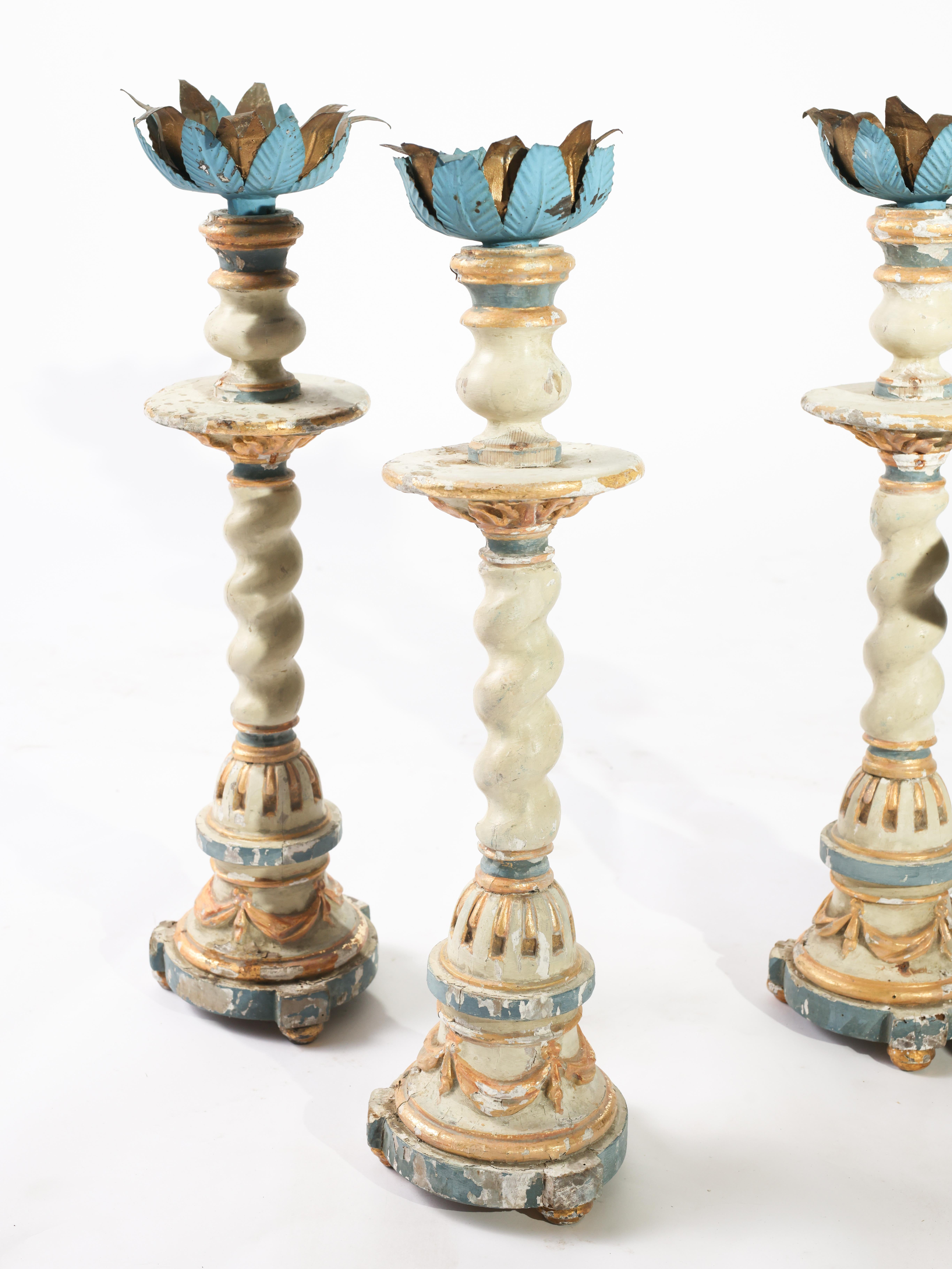Set of four stunning 17th century Portuguese altar sticks. The candlestick tops are adorned in a crown of metal leaves in gilded and blue painted finishes. The large scale candlestick bases are carved with intricate detail with a painted and gilded