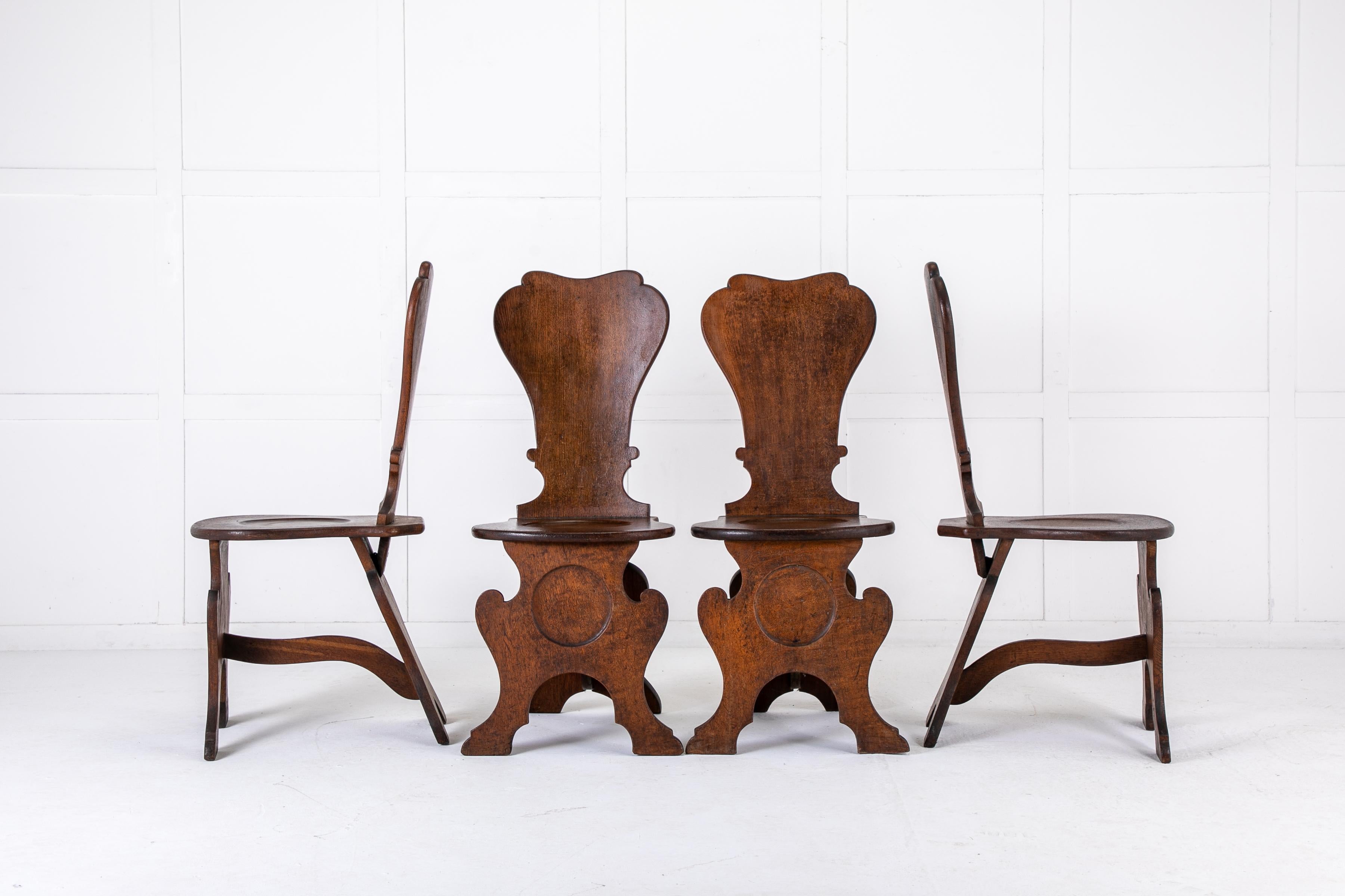 A good set of four 18th Century English oak hall chairs. Having a great shape and strong construction. In excellent overall condition, each with a high, slightly curved and waisted back, dish seat and raised on shapely front supports, united by a