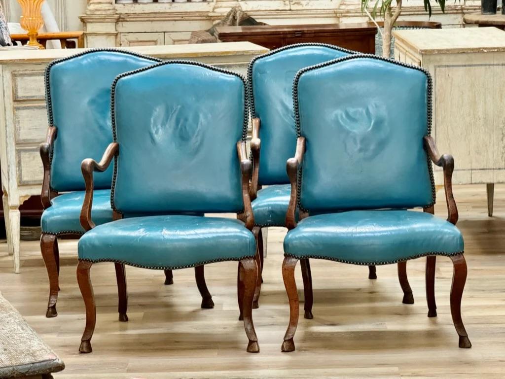 Set of four 18th Century Italian walnut armchairs, the arched crest over fine molded arms, the wide serpentine, seat over cabriole legs ending in hoof feet.  Lovely patina.  Later blue leather upholstery. 39” h. x 21.24” w x 20.75” d. SH: 17.5


