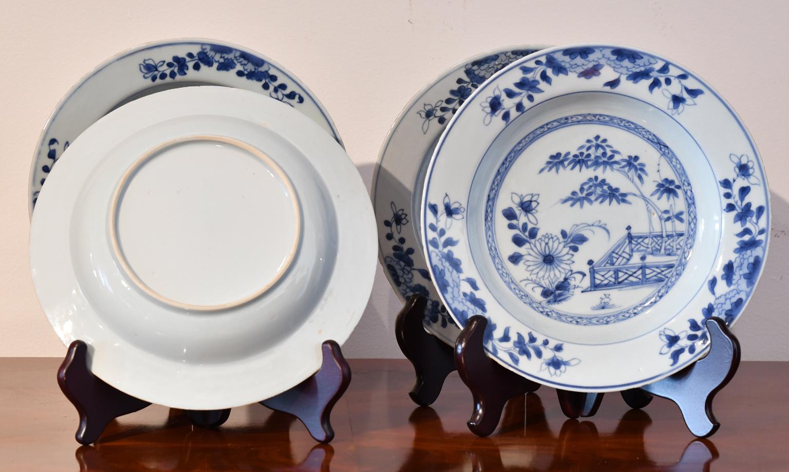 A set of four (4) Qing Qianlong porcelain ware comprising two shallow bowls and two plates with hand-painted cobalt blue decorations depicting in the central well a bamboo tree within a fenced veranda setting and other flora surrounded by a