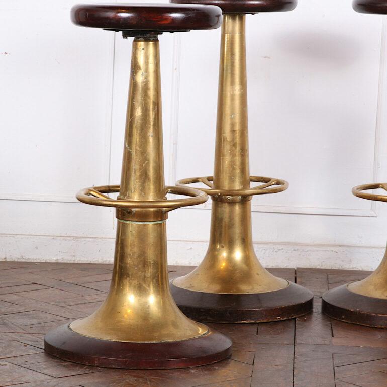 Set of four brass and mahogany bar stools, the spinning mahogany seats raised on tapering turned brass column supports with attached foot rests and standing on large round turned wooden bases.

Brass + mahogany bar stools

18? diameter x 31.5?