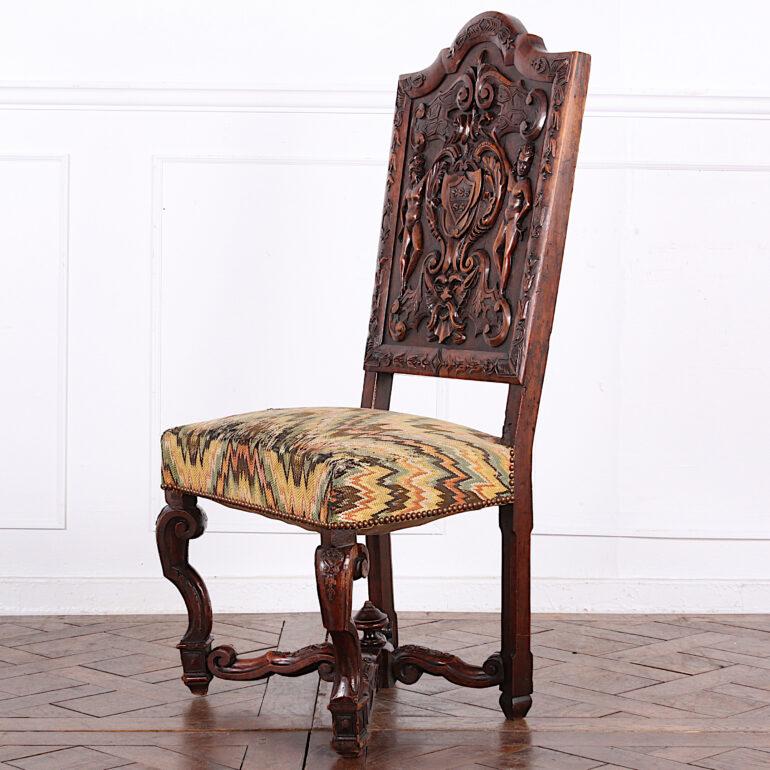 Set of four heavily carved walnut Italian chairs, the tall arched paneled backs featuring highly-detailed imagery of figures flanking a heraldic shield and surrounded with scrolls, leaves and flowers. Raised on scrolled legs united by a shaped 'X'