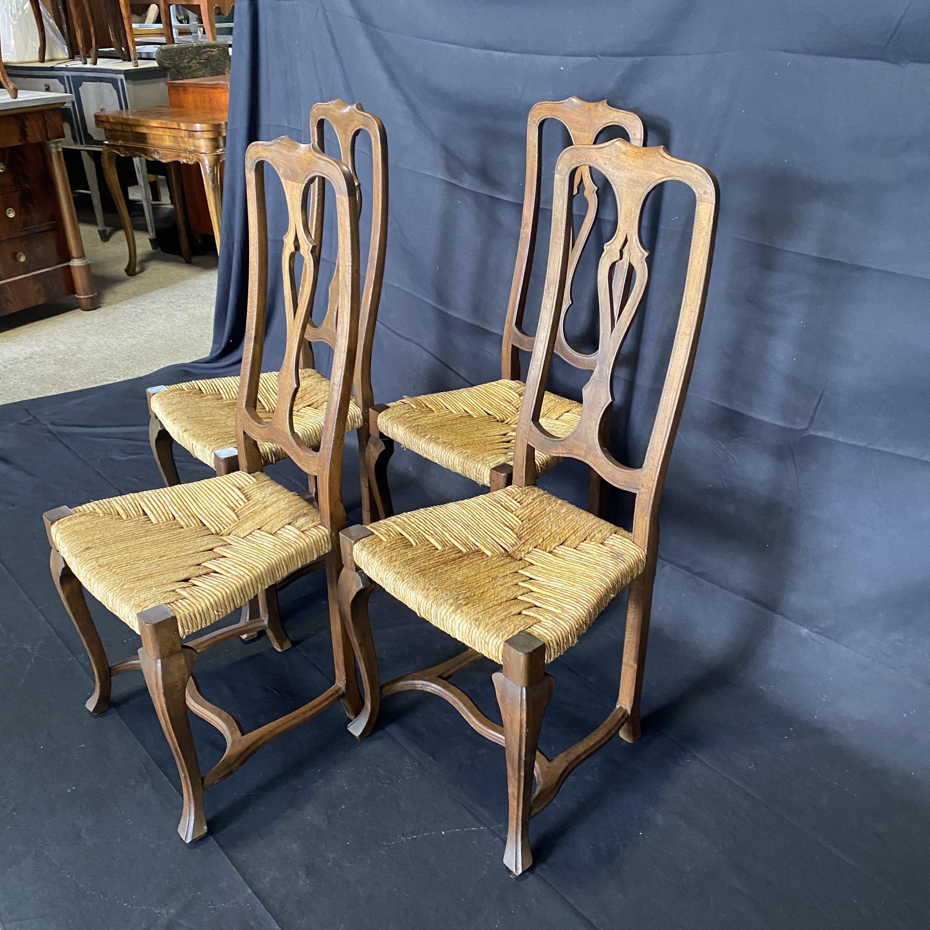 Lovely antique set of four walnut dining chairs with gorgeous patterned rush seats made in the country French provincial style. The chairs feature an aged walnut finish with a lovely patina, supported by elegant cabriole legs and feet. Classic