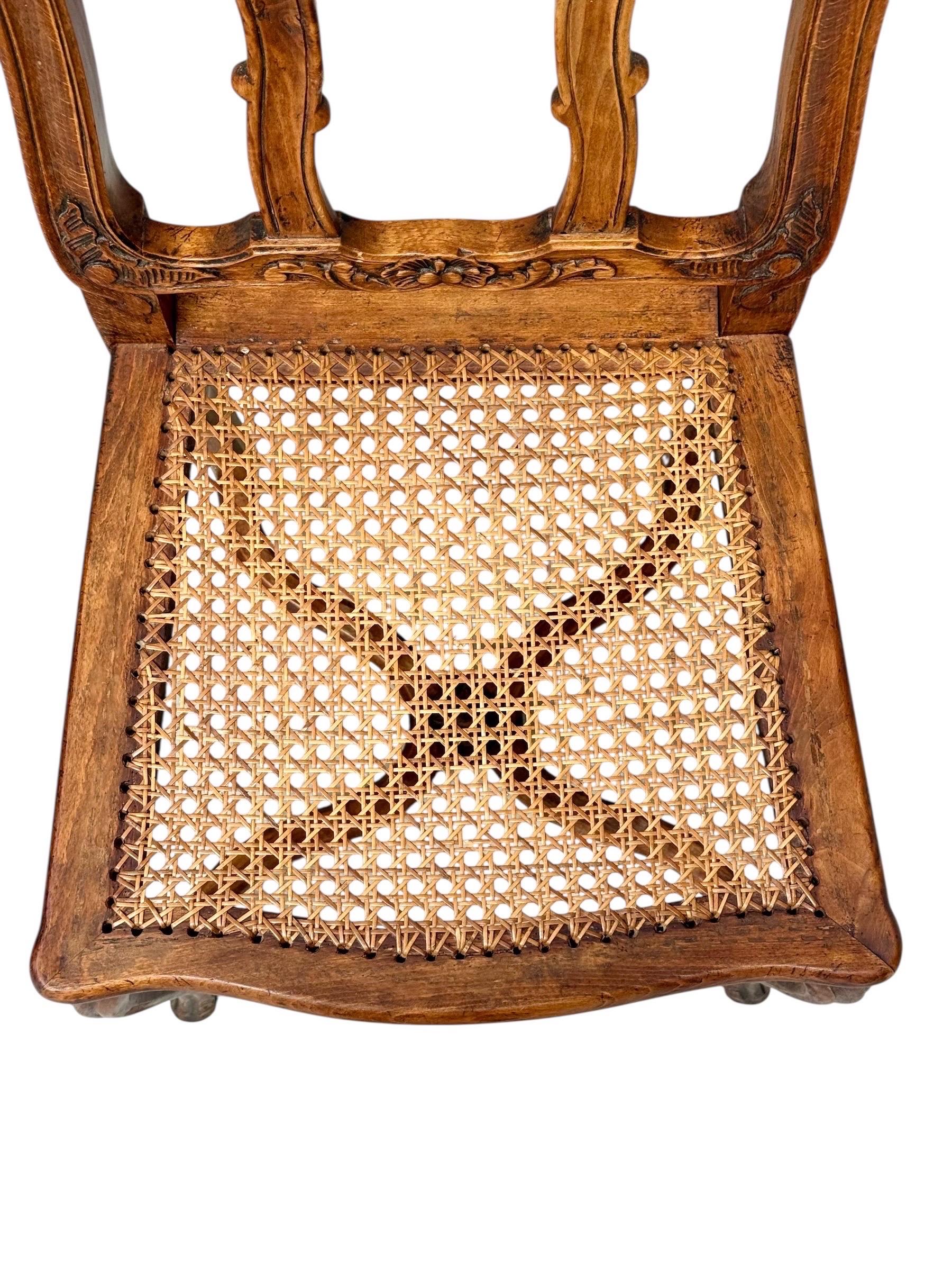 Eleganter Satz von vier französischen Esszimmerstühlen im Louis XV-Stil aus massivem Nussbaumholz, aus dem 19. Jeder Stuhl zeigt exquisite handgeschnitzte Details mit Blumen- und Muschelmotiven, die den Kamm und die Schürze zieren und