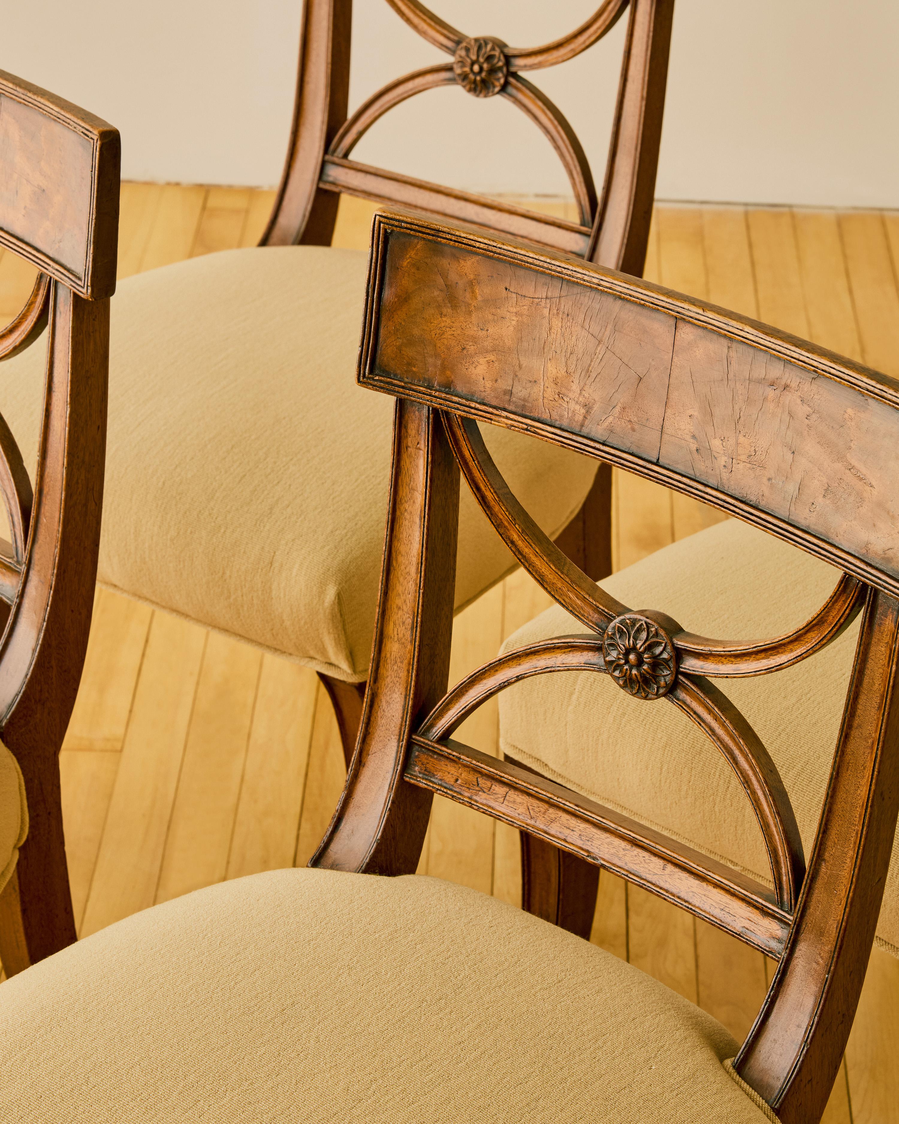 Set of four 19th century Mahogany dining chairs with upholstered seating, curule- shaped splats, and curved legs.