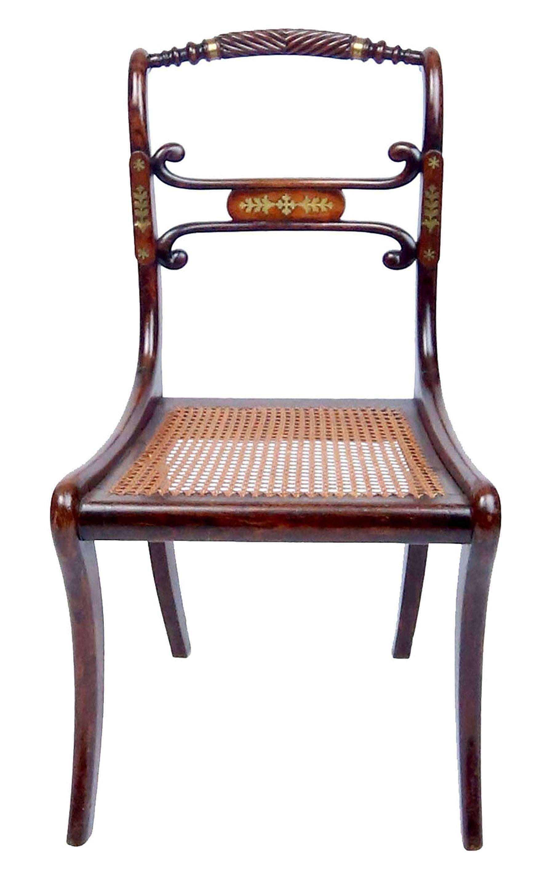 Four fine George III faux painted rosewood chairs with inlaid brass details, gadrooned crest rail, and saber legs. Original caned seats, horsehair stuffed button-tufted cushions upholstered in pink silk. One chair bears a mid-20th century sticker