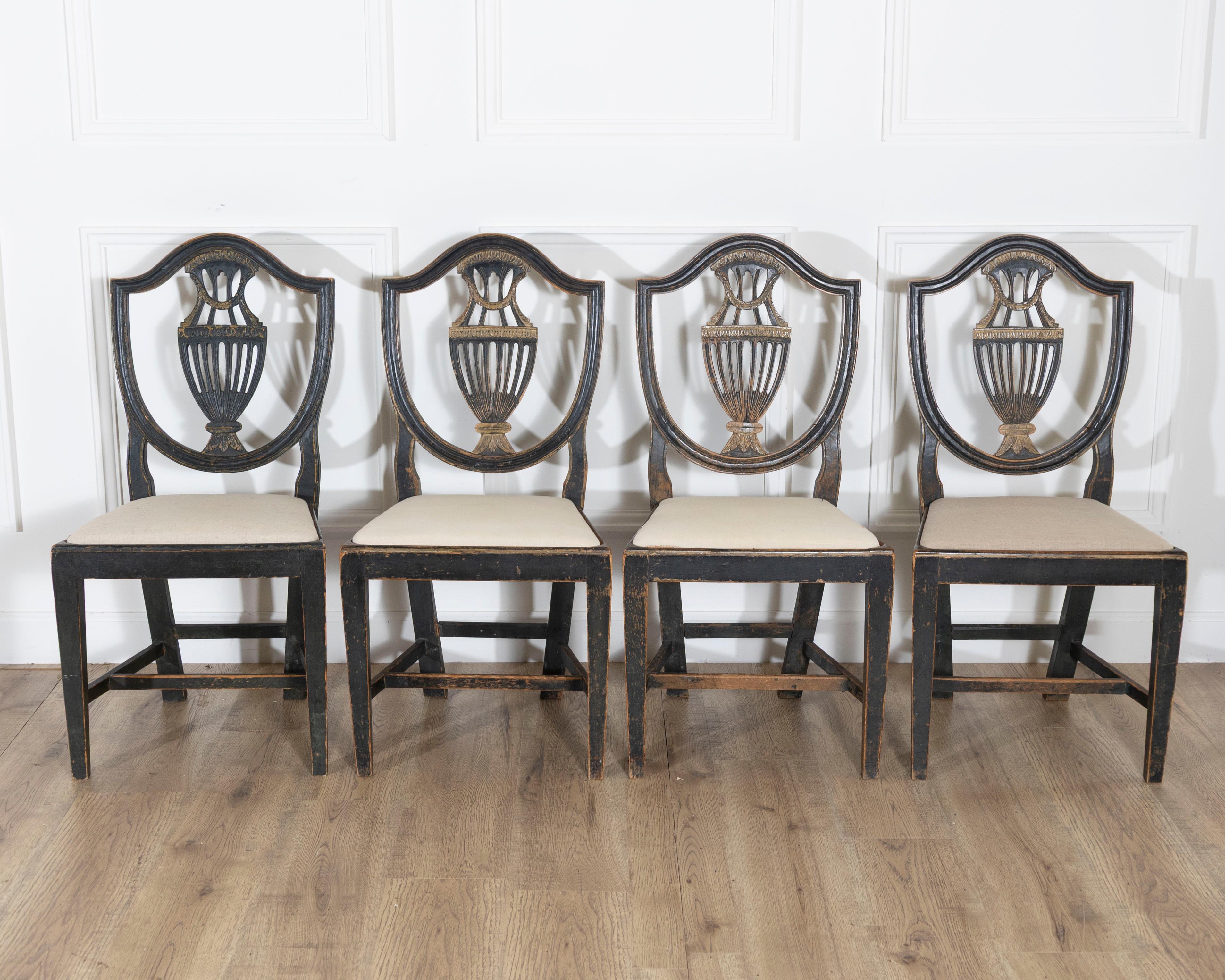 A superb suite of four 19th century Swedish chairs, each with a finely carved frame and escutcheon-shaped back centered by a stylized basin motif. The original blackened wood finish is beautifully accented with traces of gilt, creating a rich