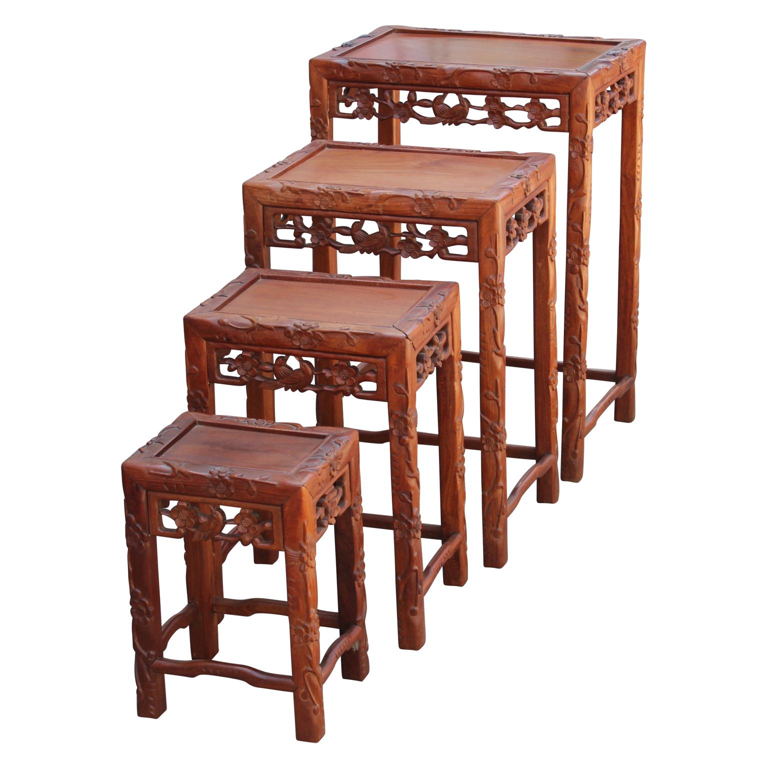 Beautiful set of four 20th century intricately carved nesting tables. They are Chinese in origin and are made from a stunning camphor wood. The tables feature carvings on the sides, legs, and table tops. The tables can be placed separately or
