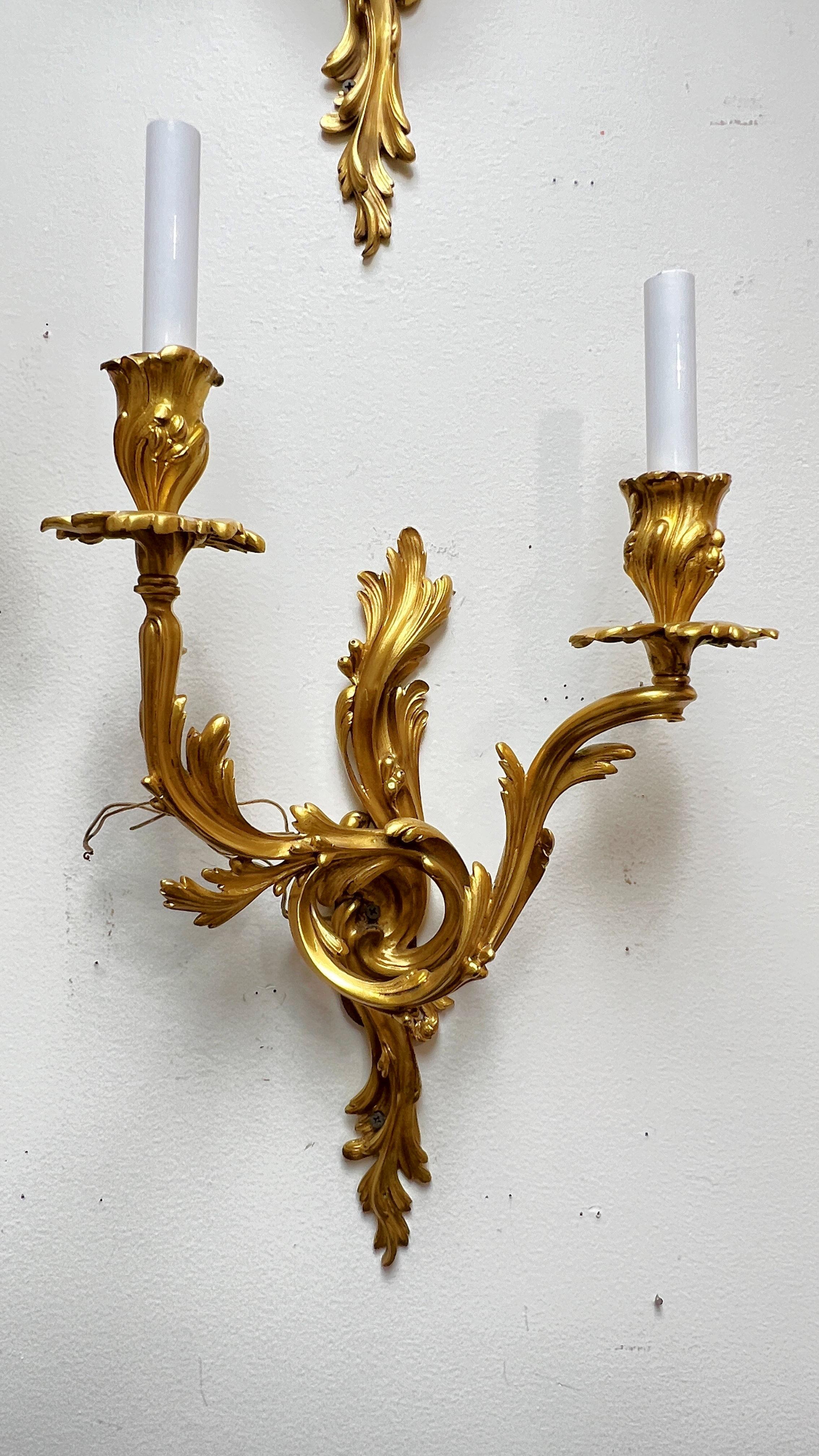 Notre ensemble de quatre appliques en bronze finement coulé et doré, de style Louis XV Rococo français, mesure chacune 22  Ils sont en bon état, avec des douilles de taille candélabre, des fils et des couvercles de bougie en plastique blanc.