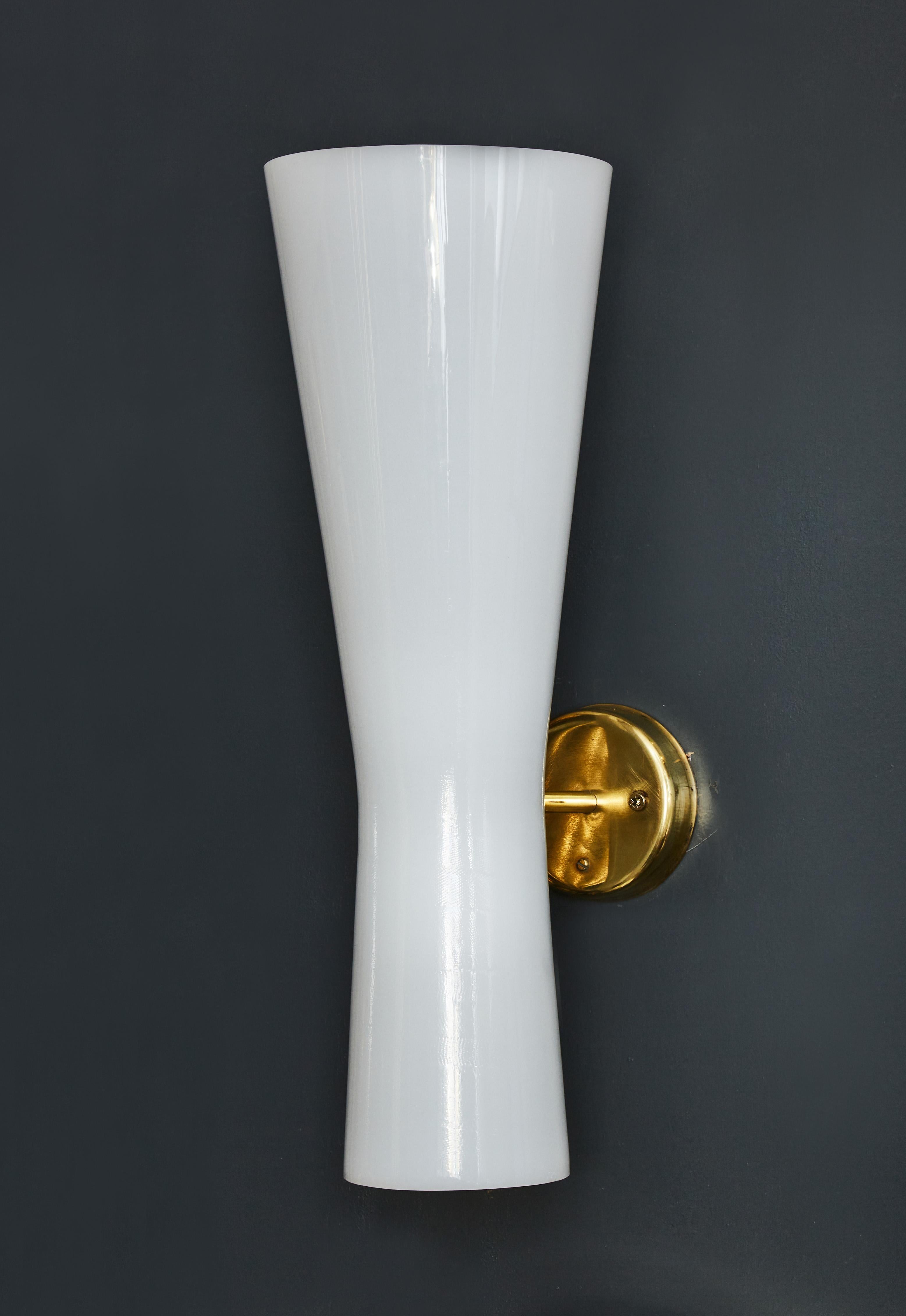 Set of four chic and pure wall sconces made of brass settings and a piece of bent white acrylique forming two cones each housing a light source.