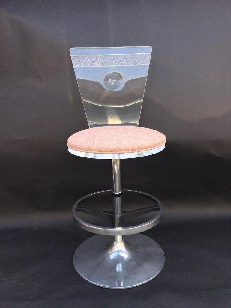 Set of four vintage swivel bar stools, crafted in the U.S.A. during the 1980's. Each stool features a sleek combination of clear acrylic and polished metal bases, complemented by upholstered fabric cushions for comfort and style.
The minimalist