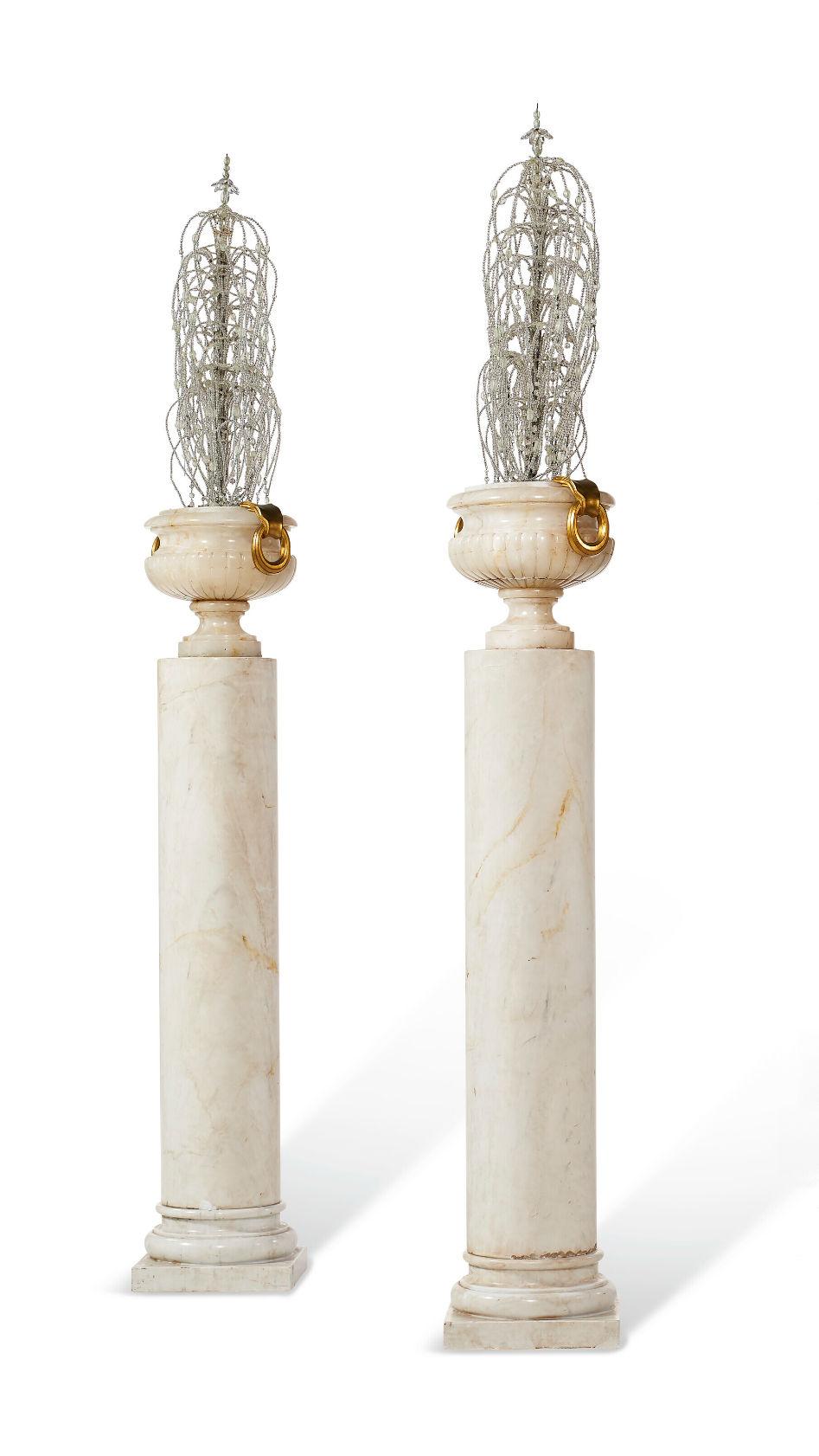 Our set of four neoclassical alabaster urns with ormolu bronze mounts, of northern European origin and dating from the early 20th century, feature cascading molded and beaded glass ornaments in the style of fountains and are mounted on pedestals.