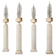 Ensemble de quatre urnes en albâtre avec ornements en verre perlé sur piédestaux