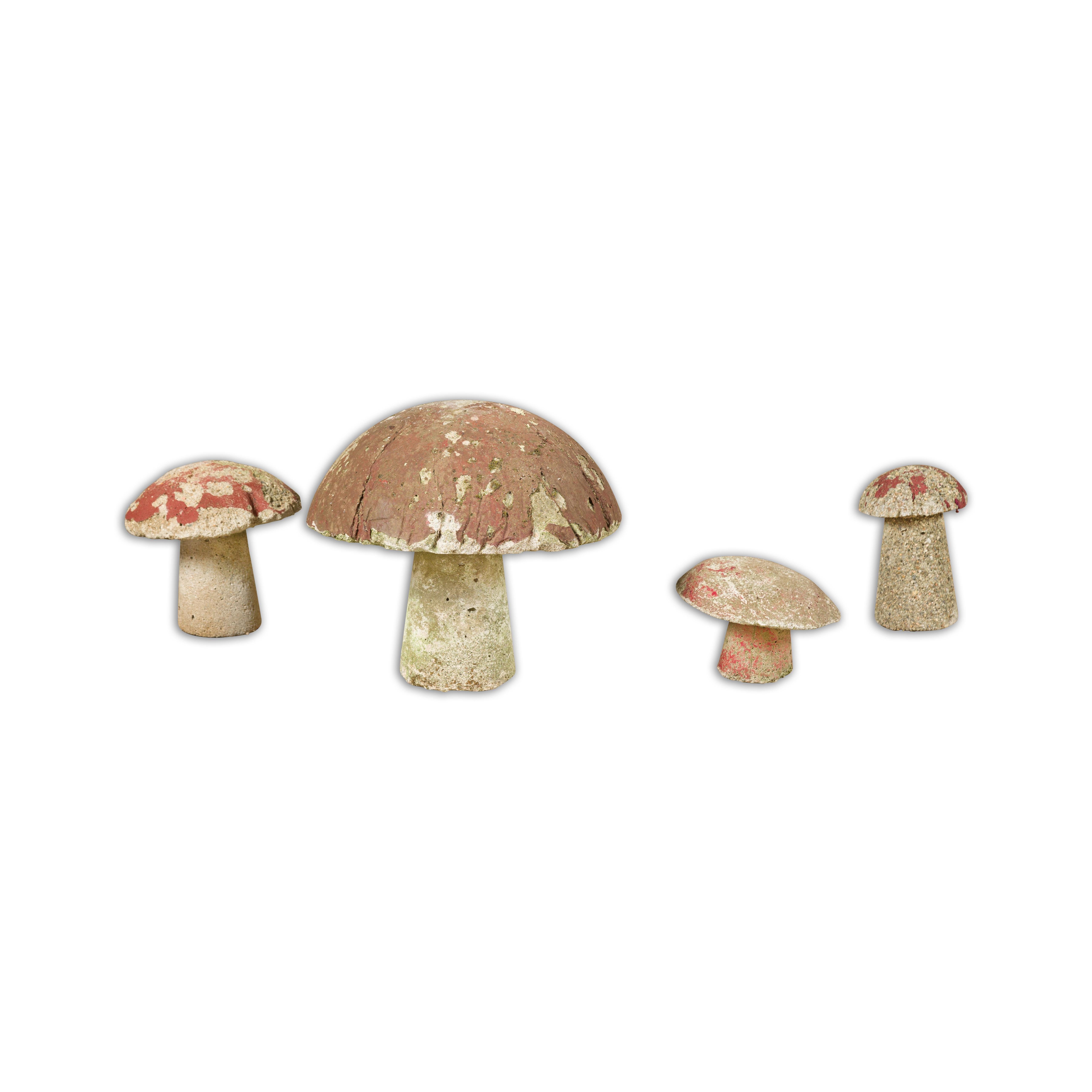A set of four American Midcentury painted concrete mushroom garden ornaments with red tops and nicely weathered appearance. Whimsically inviting, this set of four American Midcentury painted concrete mushroom garden ornaments lends an enchanting