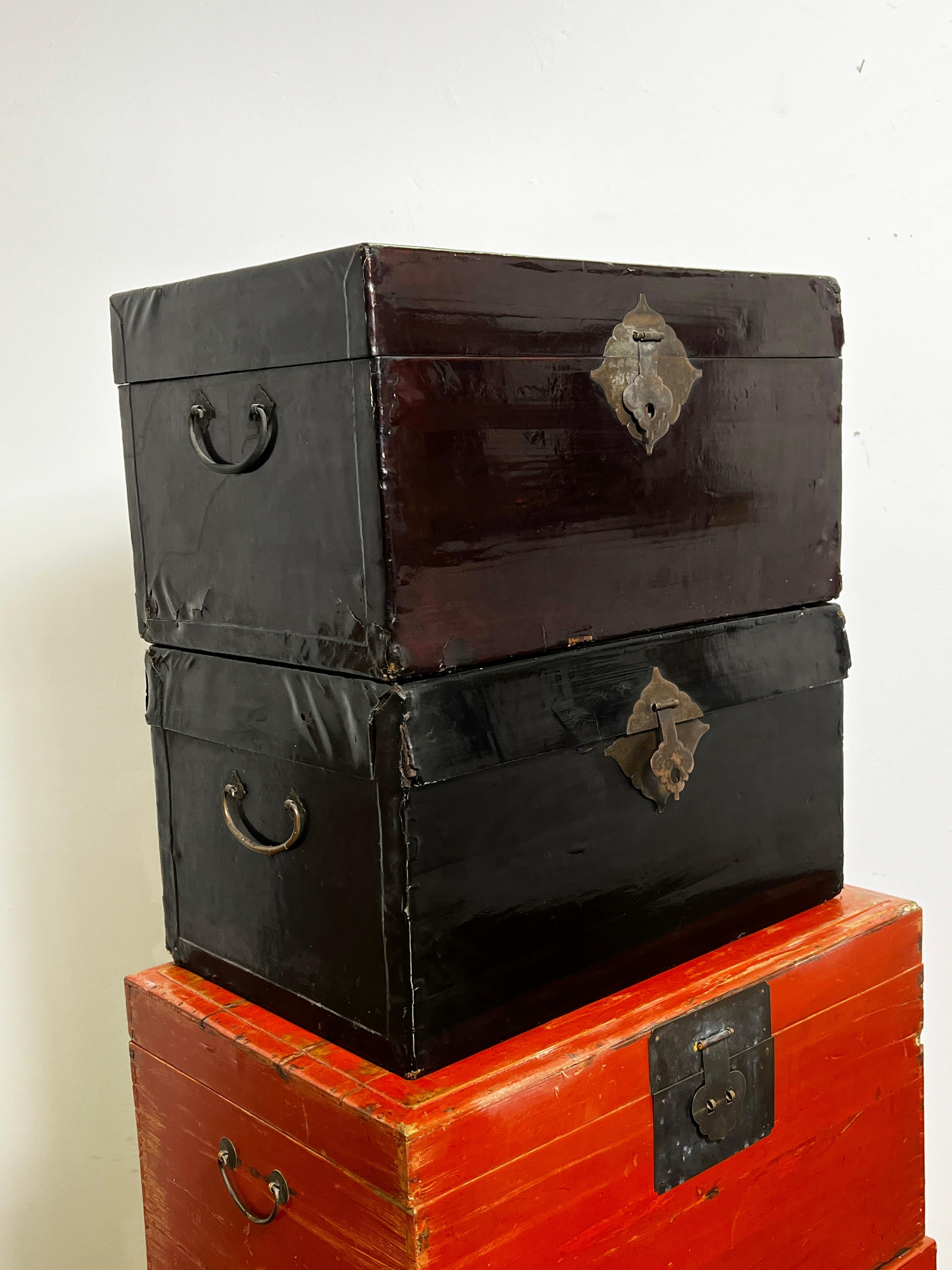 Una colección de cofres chinos de finales del siglo XIX y del XX incluye un cofre de madera de olmo lacado en bermellón sobre peana (abajo), encima un cofre de madera de cedro lacado en rojo escarabajo; y arriba: un par de cofres de lino lacado en
