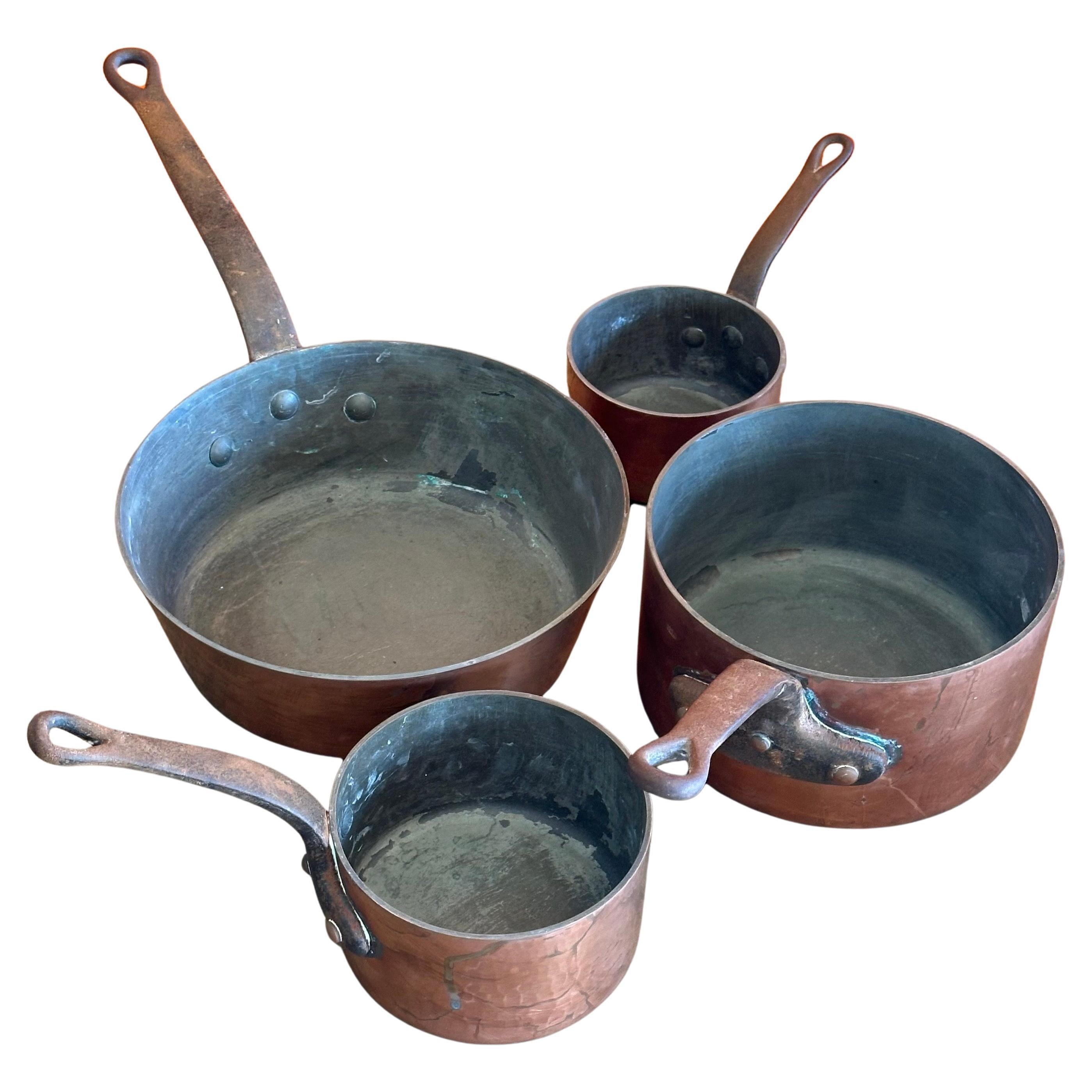 Raro juego de cuatro ollas francesas antiguas de cobre con tapa, de principios del siglo XX. Cada pieza es de cobre martillado a mano con asas de hierro forjado remachadas.  Es difícil encontrar un juego completo con tapas.  Las macetas miden lo