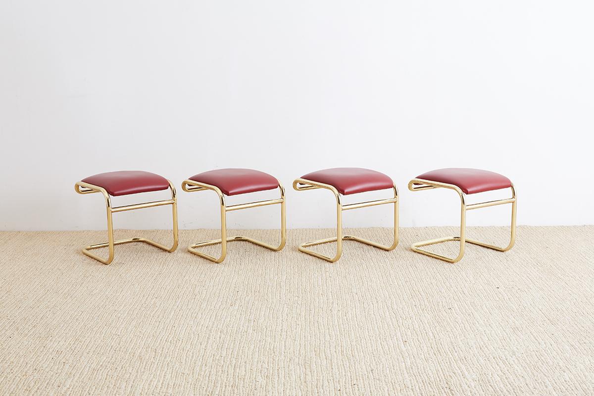Red and gold set of four cantilever stools or ottomans designed by Anton Lorenz and produced by Thonet. Interesting modern interpretation of the German Bauhaus design featuring a gold anodized, chrome steel cantilever frame upholstered in a red