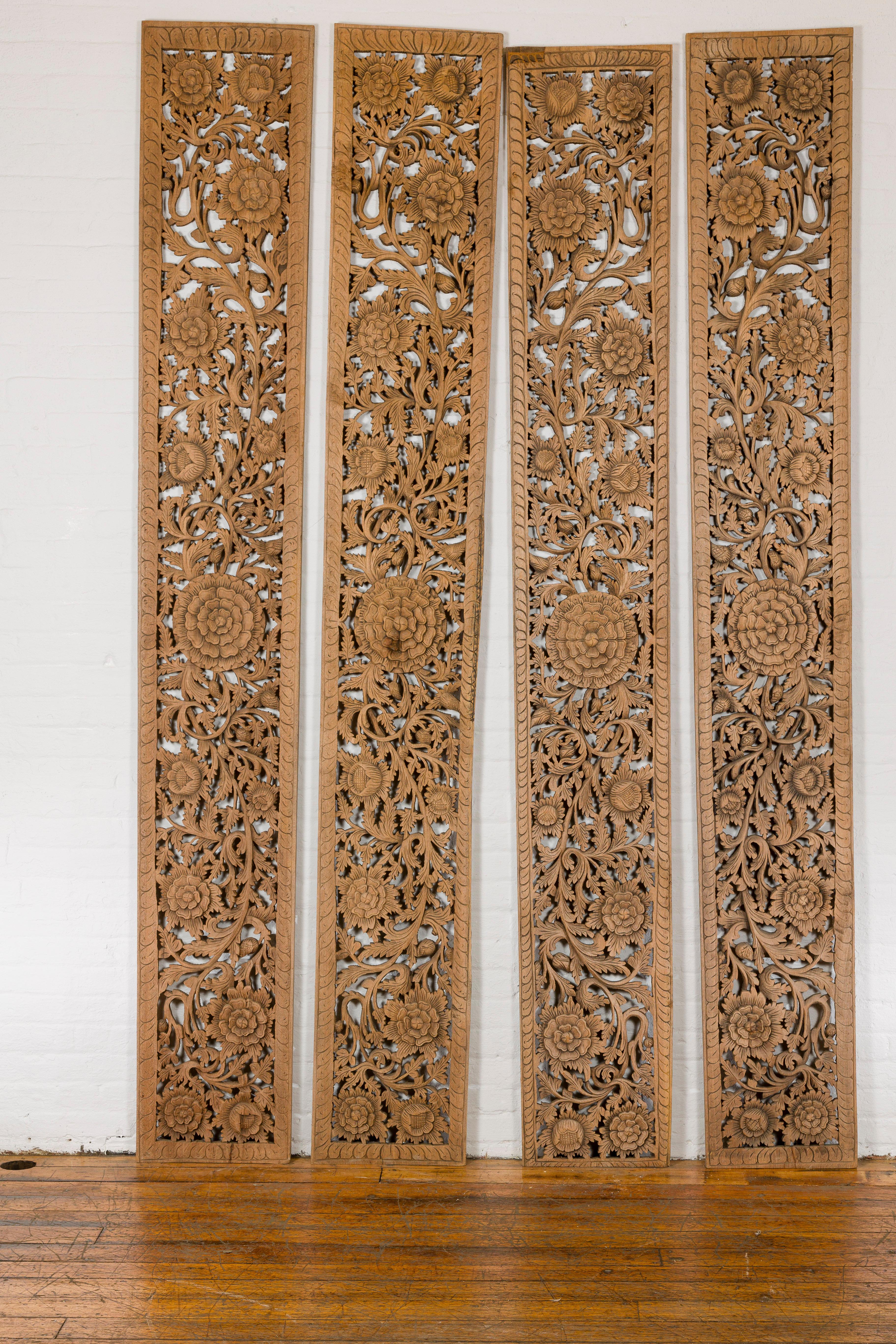 A set of four carved wooden architectural panels from the mid 20th century with large flowers and scrolling foliage. Delve into the artistic intricacy of this set of four carved wooden architectural panels from the mid 20th century, each piece a