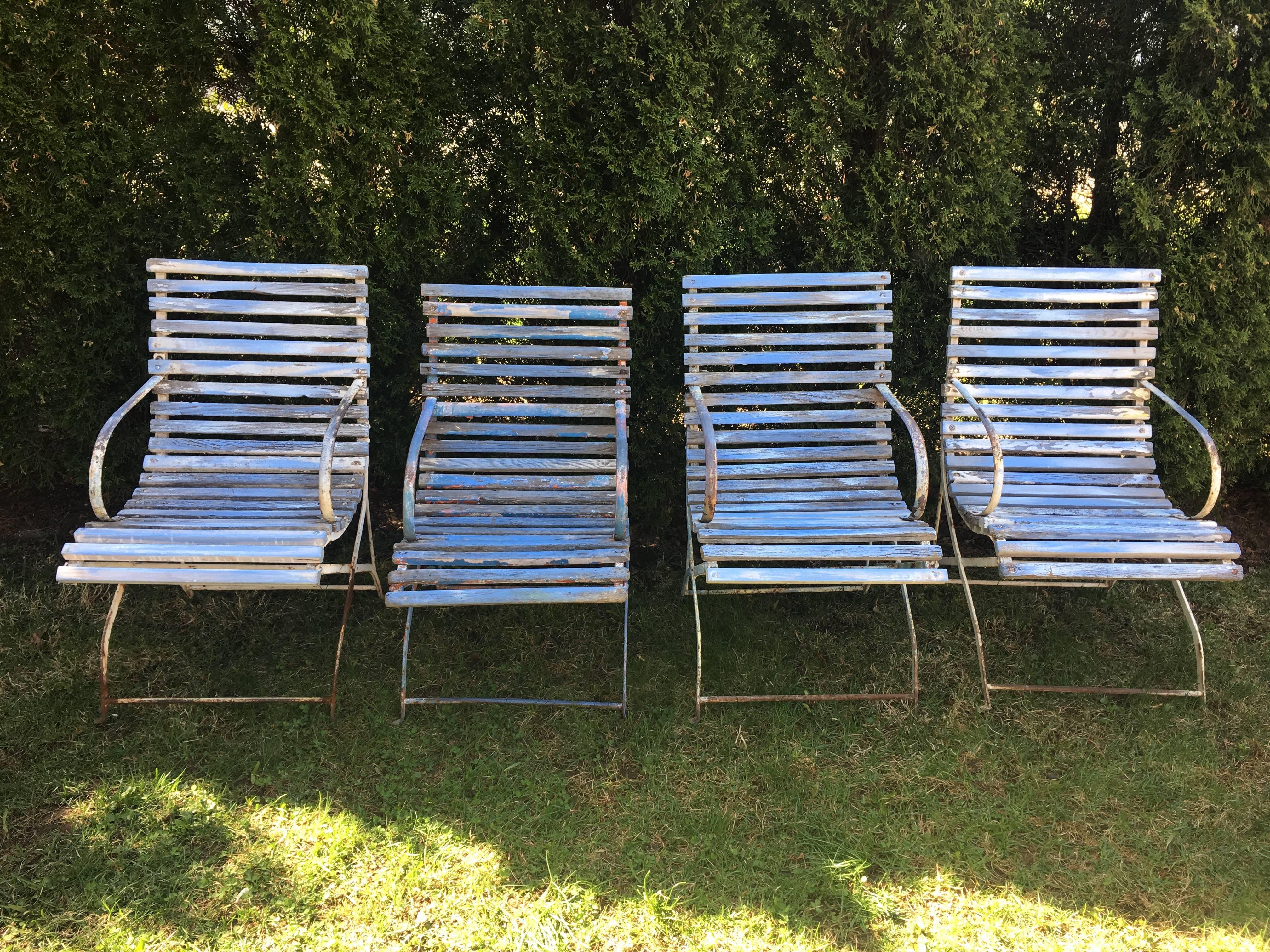 These supremely comfortable armchairs came from the famed Promenade des Anglais on the Nice waterfront in France. Their wrought iron frames are in original painted condition, but some of the oak slats have been replaced and colored to match the