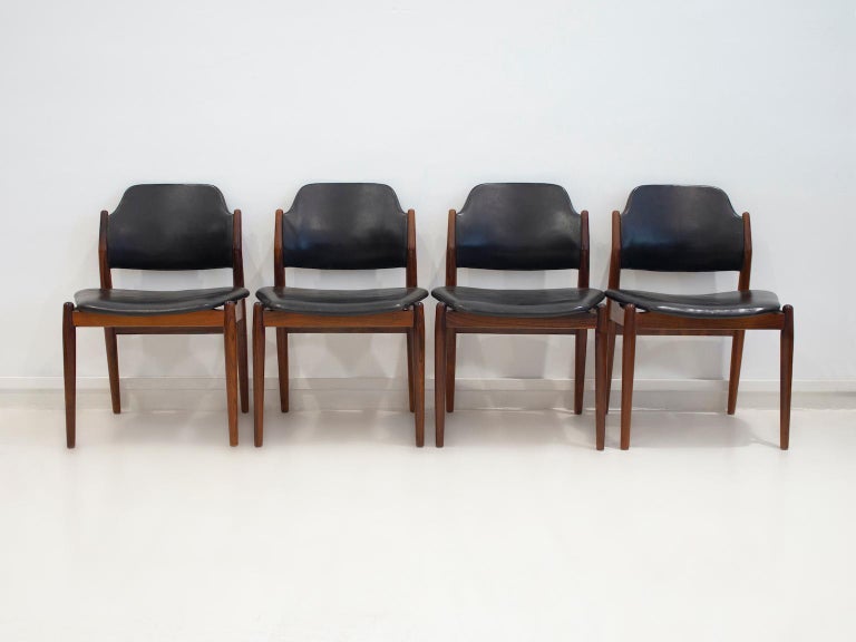 Set of four Arne Vodder hardwood chairs, model 462. Seat and back upholstered in black leather with some patina from age and use. Manufactured in Denmark by Sibast Furniture. The chairs feature a timeless design with a slightly curved back for