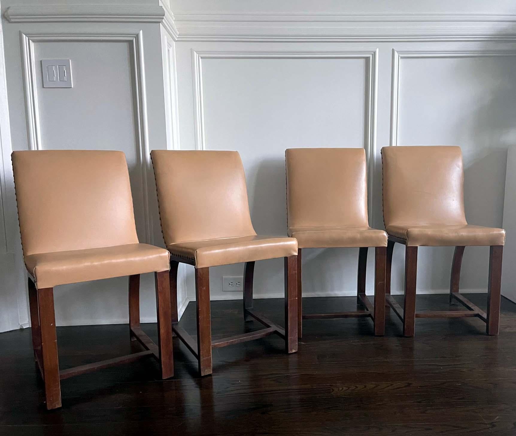 A set of four chairs designed in 1930s by Gilbert Rohde for Heywood Wakefield Gardener MA. Mahogany construction with arched back support. Cream color naugahyde upholstery with decorative brass taps is likely original. All labeled as shown.
    