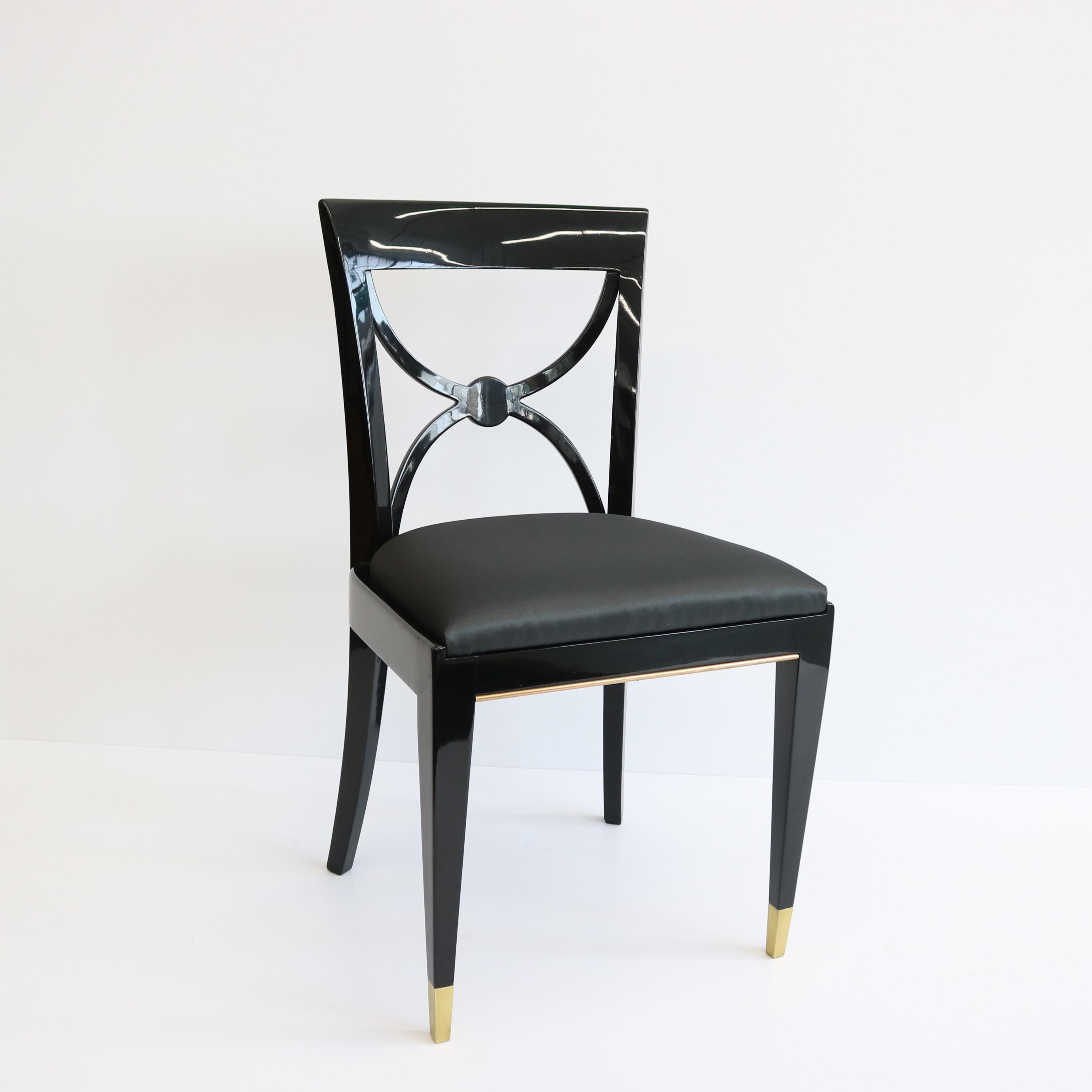 Un ensemble remarquable de quatre chaises de salle à manger Art déco conçues par De Coene Frères.  Montures en laque noire avec sabots en bronze patiné aux pieds avant et garniture en laiton au bas de la barre d'assise.  L'élégant double fond
