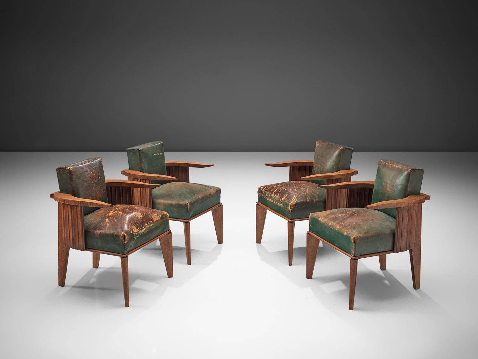 Set of four French/ Belgium easy chairs in wood and patinated green leather, France, 1920s. 

This unique design features cow horn-shaped armrests, thick cushions and carved, closed sides. The two legs in the front of the chair are slightly turned