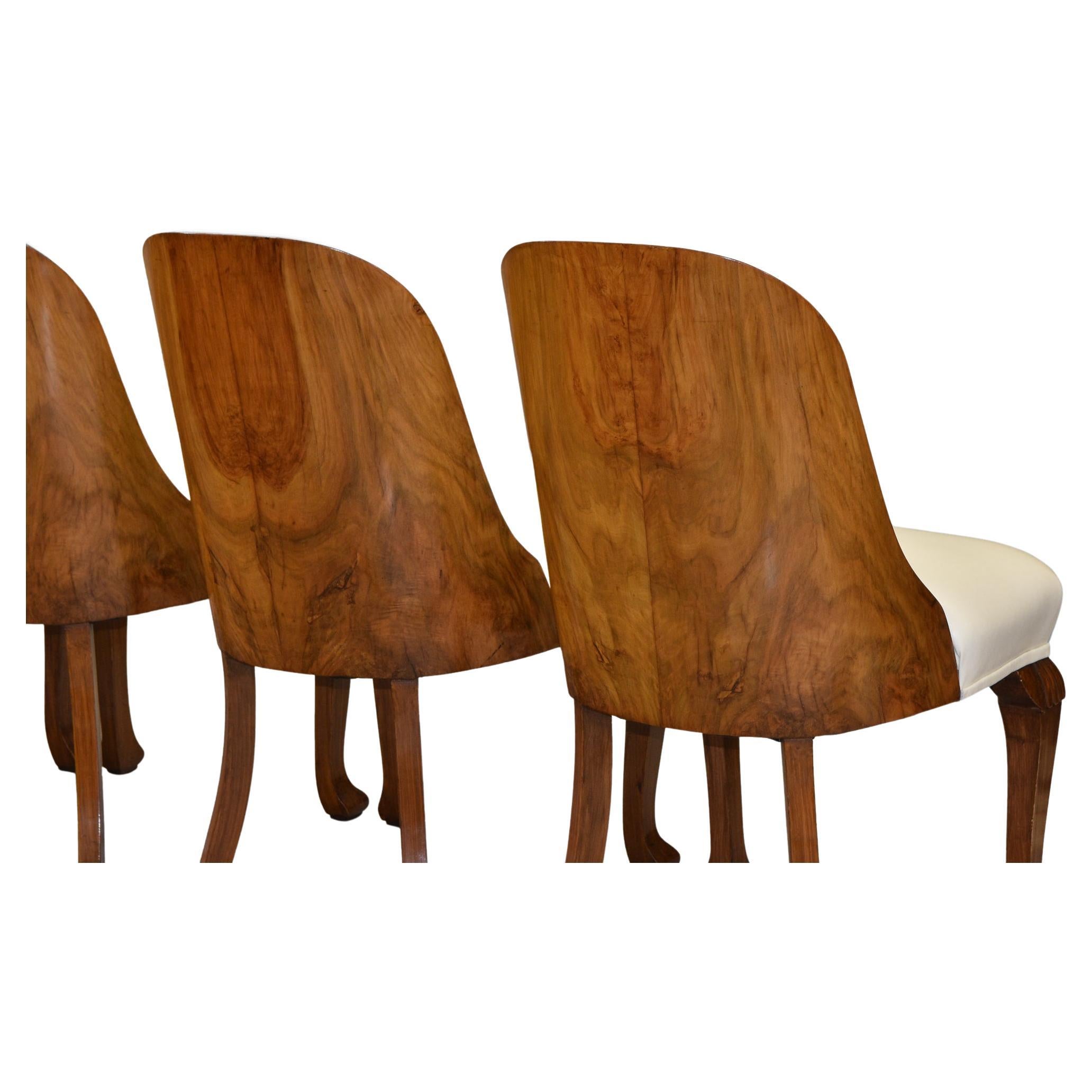 A superb set of four Art Deco walnut shaped-back dining chairs with leather seating. Circa 1930's.

The walnut frames have been cleaned and are in very good condition, showing some light signs of use with age. The backs showing wonderful bookmatch
