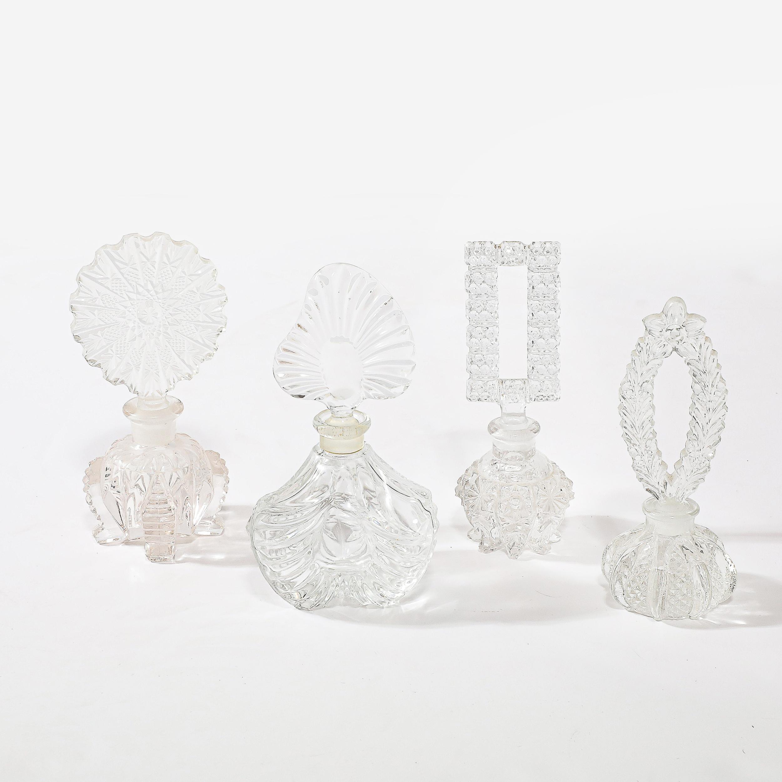 This remarkable set of four assorted Art Deco pressed glass perfume holders showcases the exquisite craftsmanship and design innovation of Czechoslovakian artisans from the 1930s. Each bottle features unique detailing, from intricate geometric