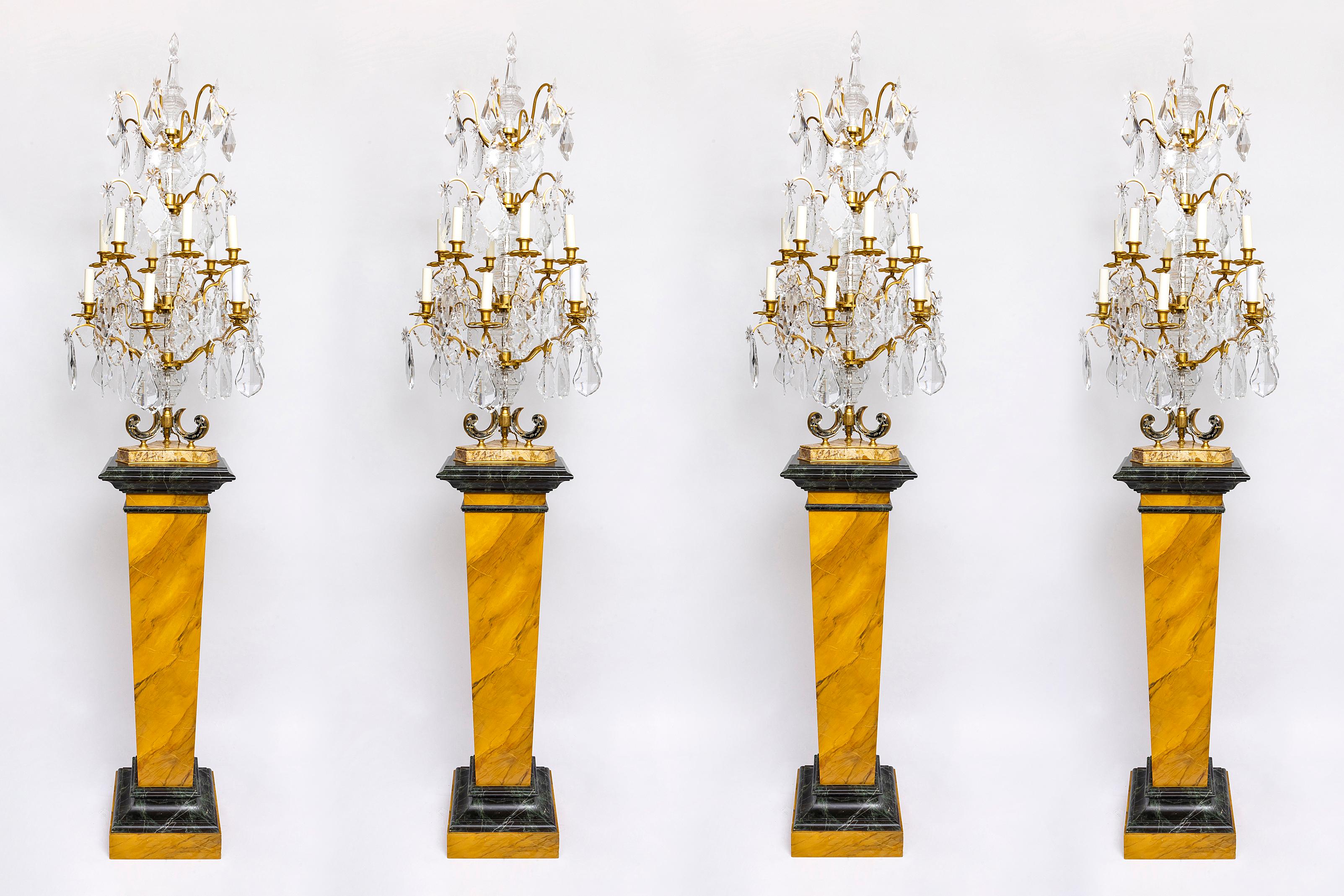Quatre monumentales girandoles à bras multiples en cristal de Baccarat du 20e siècle sur piédestal en faux marbre peint à la main, attribuées à la Maison Jansen.  Chaque girandole se compose de deux rangées de bras qui s'étendent à partir d'un corps